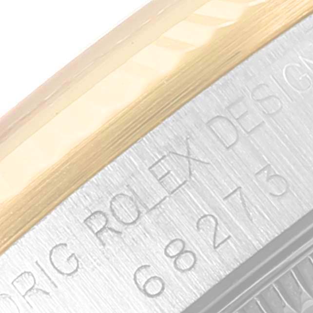 This close-up image shows the side of a Rolex Mid-Size 68273 Women
s Steel and Gold (two tone) Champagne Dial 68273 Women
s Steel and Gold (two tone) Champagne Dial watch with part of its model number and "ROLEX DESIGN" engraving.