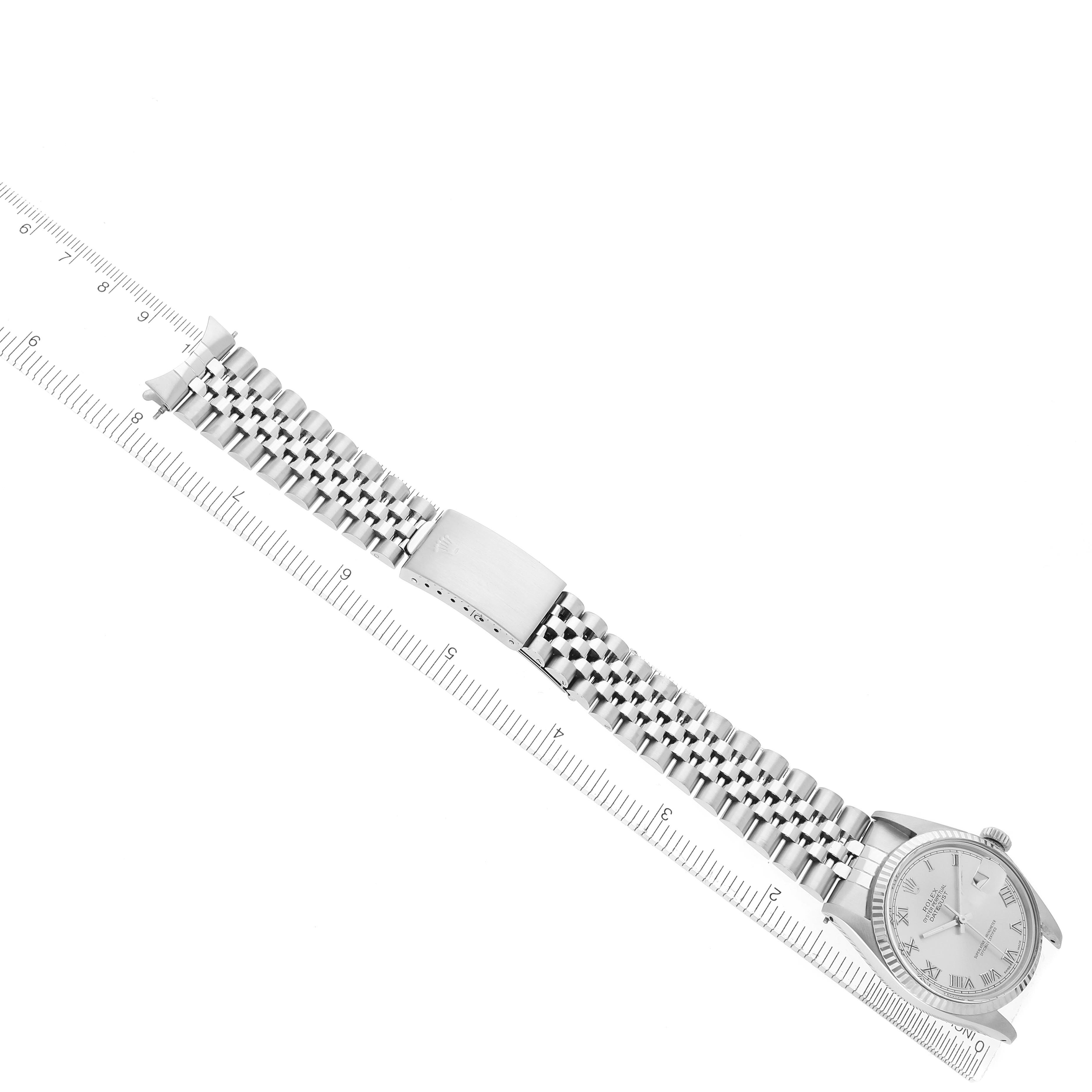 The Rolex Datejust 16014 Men
s Stainless Steel Silver Dial 16014 Men
s Stainless Steel Silver Dial watch is shown from a top-down angle, highlighting its dial, bracelet, and clasp alongside a ruler.