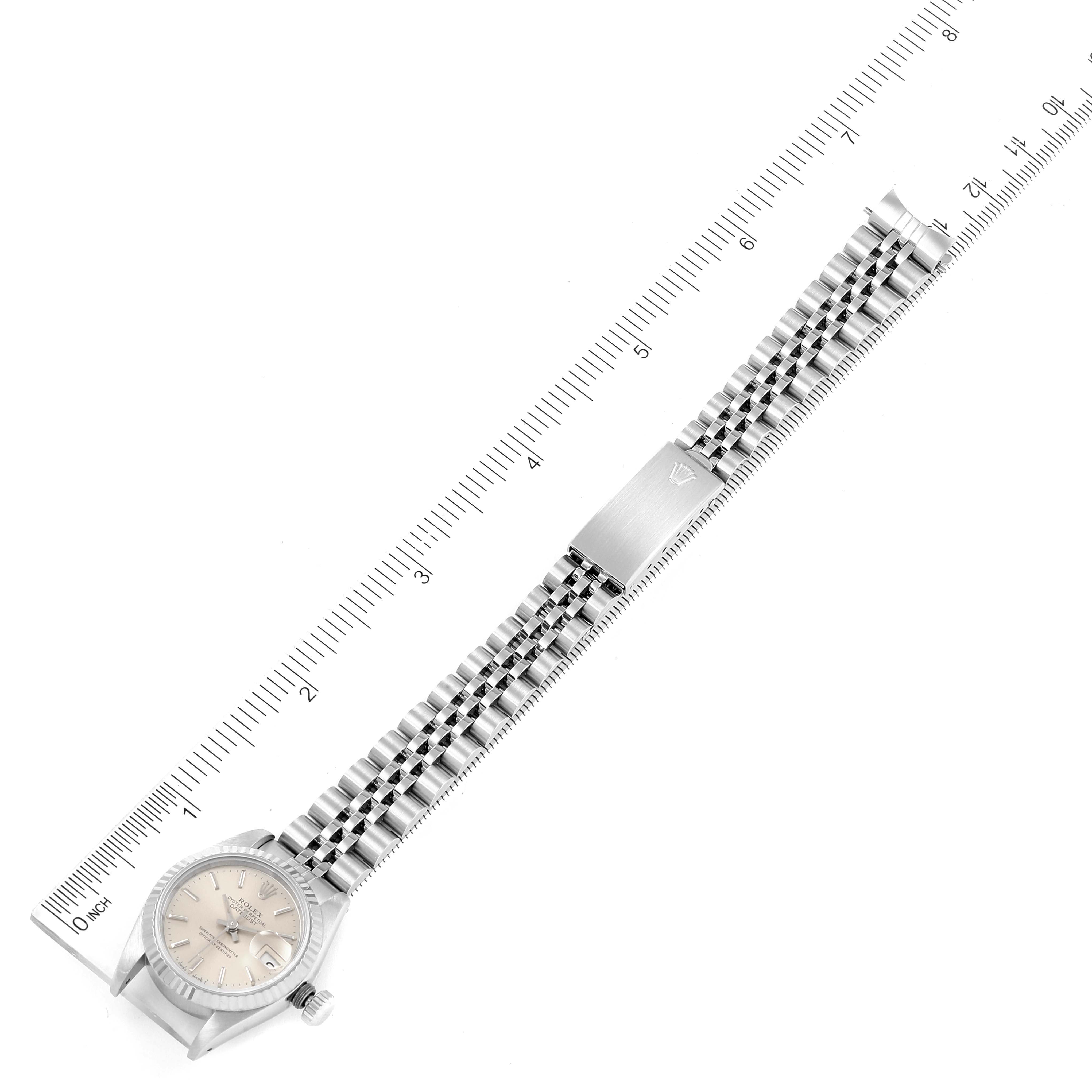 The image shows a top-down view of a Rolex Datejust 69174 Women
s Stainless Steel Silver Dial 69174 Women
s Stainless Steel Silver Dial watch with a Jubilee bracelet and a measurement ruler.