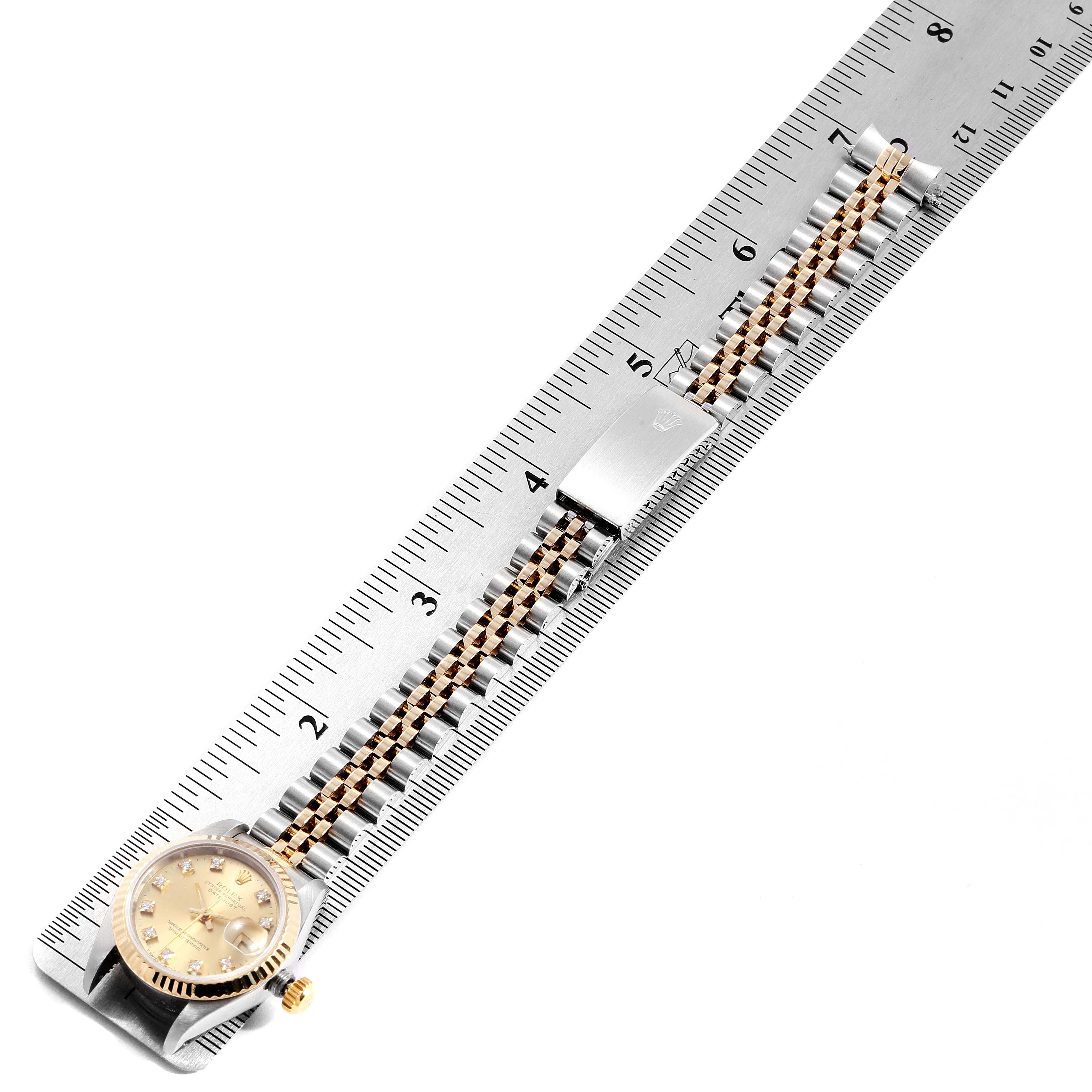 A Rolex Datejust 69173 Women
s Steel and Gold (two tone) Champagne Dial 69173 Women
s Steel and Gold (two tone) Champagne Dial watch is photographed from a top-down angle, showing its dial, bracelet, and clasp, with a ruler for scale.