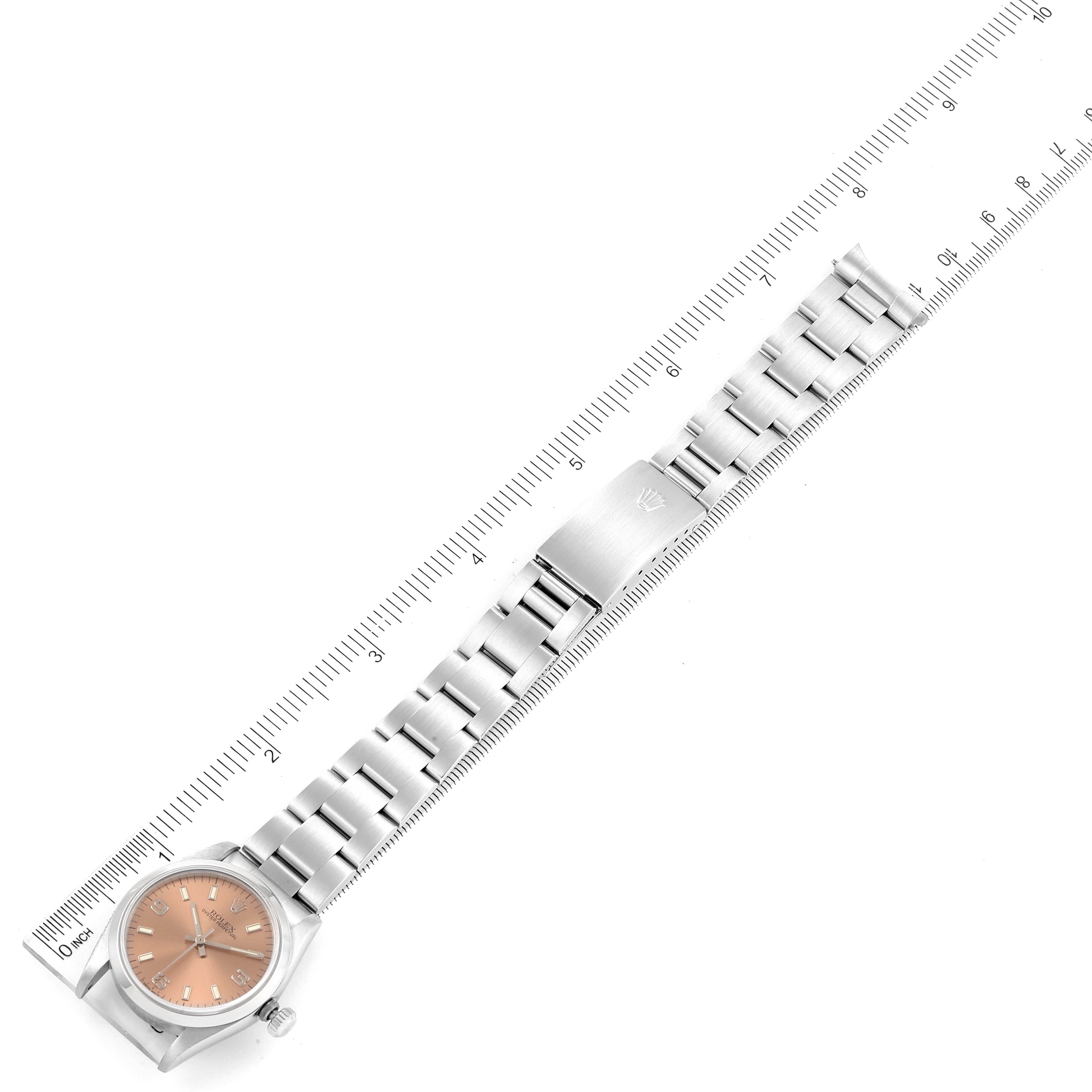This image shows a full view of the Mid-Size Rolex watch laid flat with the face, case, and metal bracelet visible, next to a ruler.