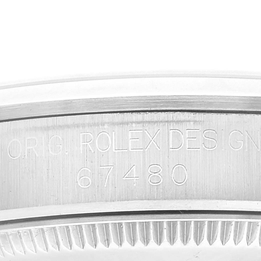 The image shows a close-up of the engraved side of the Rolex Mid-Size 67480 Women
s Stainless Steel White Dial 67480 Women
s Stainless Steel White Dial model watch, displaying the model number 67480.