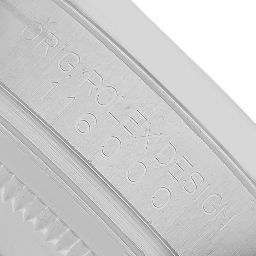 This close-up image shows the engraved inner bezel or rehaut of the Rolex Oyster Perpetual 116000 Men's Stainless Steel Silver Dial watch.