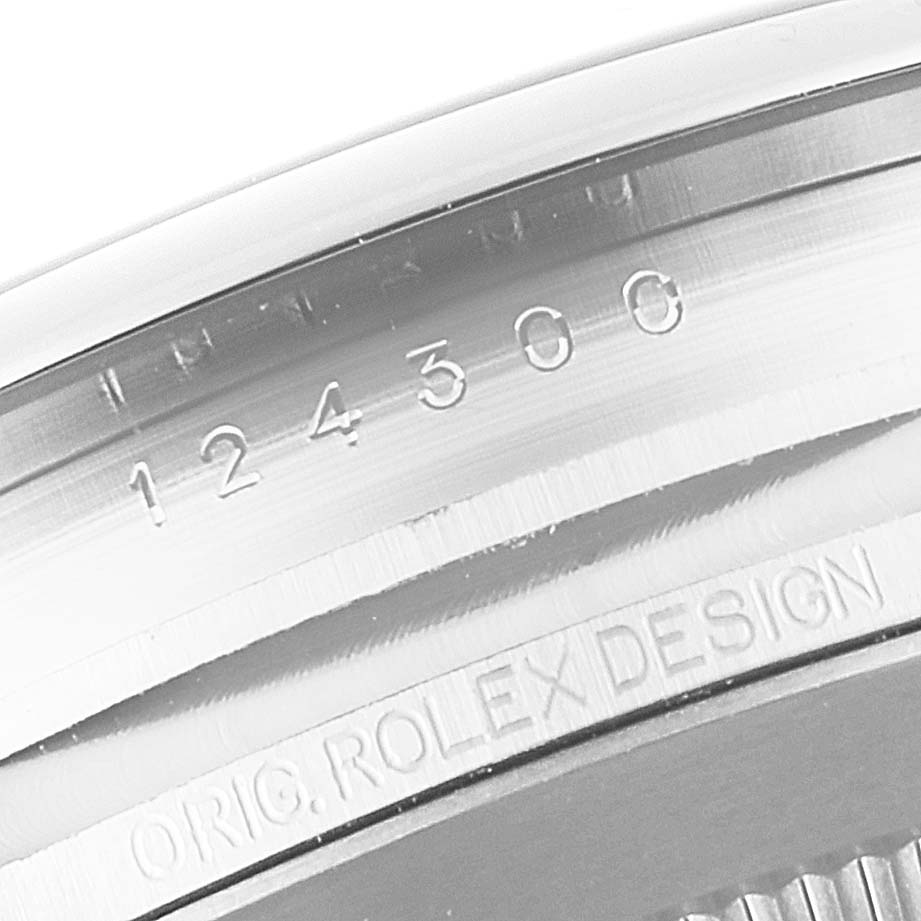 This image shows a close-up of the engraved case back of a Rolex Oyster Perpetual 114300 Men
s Stainless Steel Blue Dial 114300 Men
s Stainless Steel Blue Dial watch, displaying the model number and "Orig. Rolex Design".