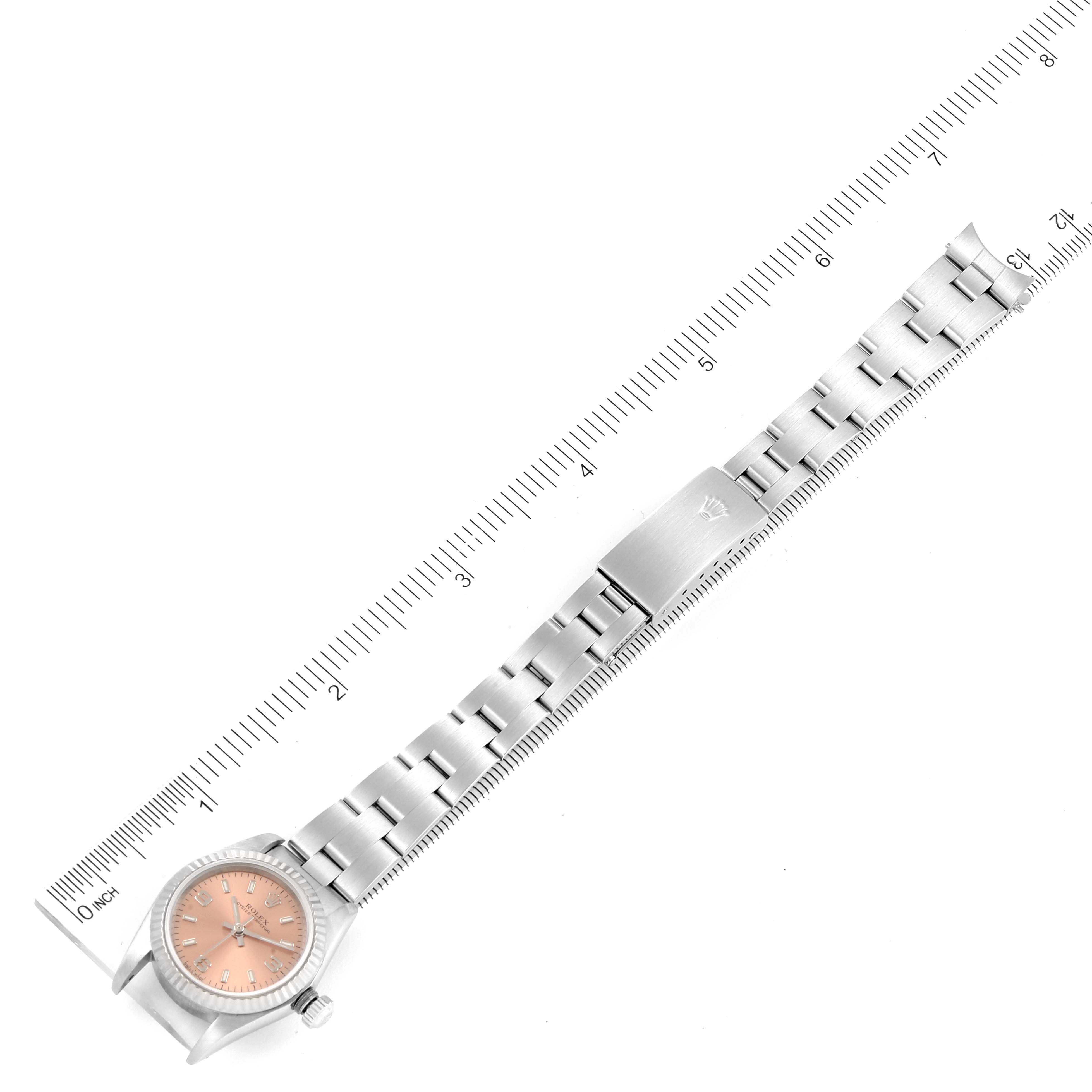This image shows a top-down view of a Rolex Oyster Perpetual 76094 Women
s Stainless Steel Pink Dial 76094 Women
s Stainless Steel Pink Dial watch and its full metal bracelet with a ruler for scale.