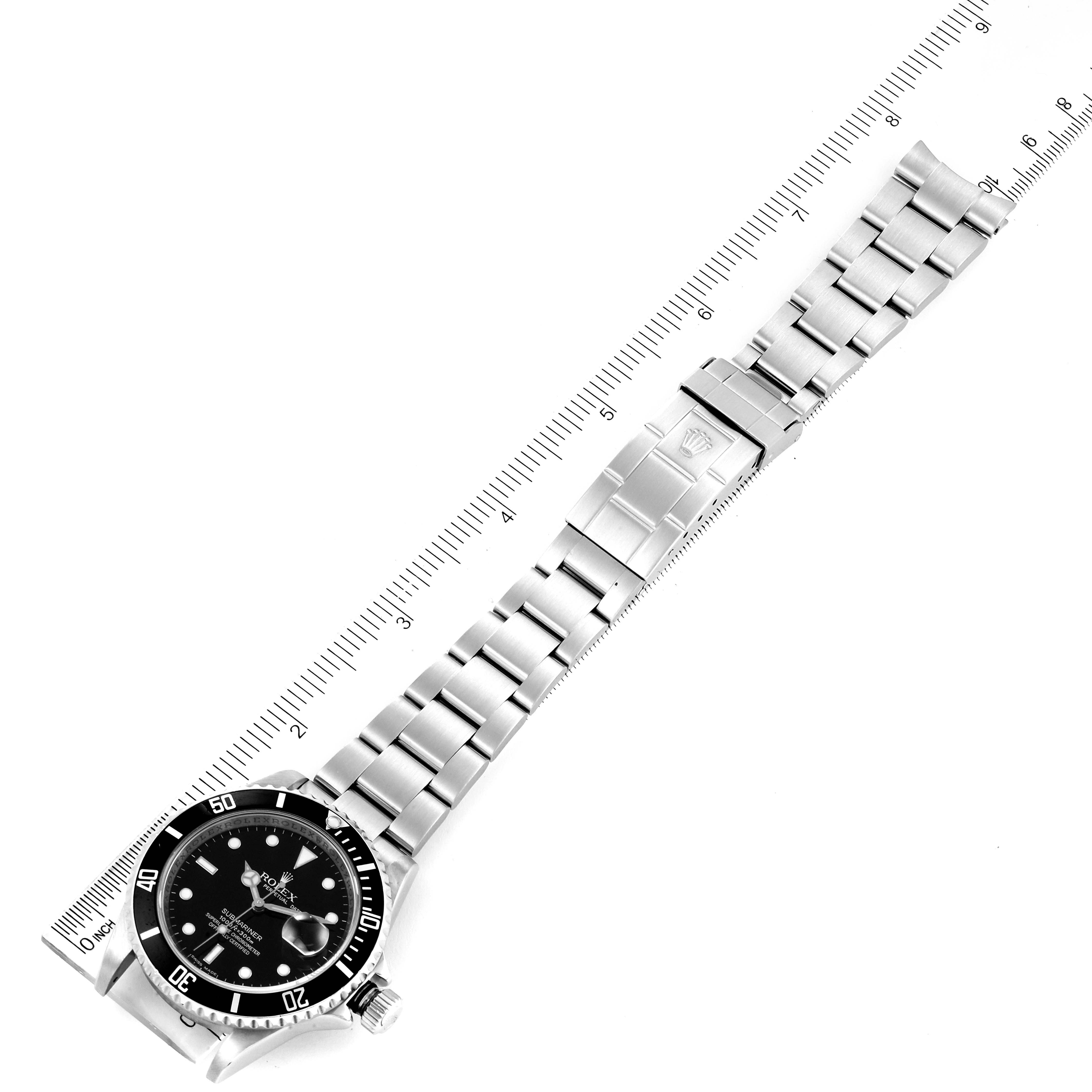 The Rolex Submariner 16610 Men
s Stainless Steel Black Dial 16610 Men
s Stainless Steel Black Dial watch is shown from an overhead angle, displaying the face, bezel, bracelet, and clasp with a ruler for scale.