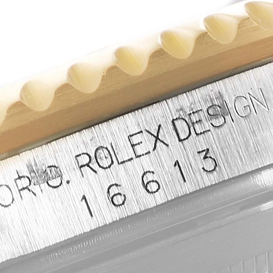 This close-up image shows the model number "16613" and "Rolex Design" engraving on the side of the Rolex Submariner 16613 Men
s Steel and Gold (two tone) Blue Dial 16613 Men
s Steel and Gold (two tone) Blue Dial watch case, including part of the bezel.