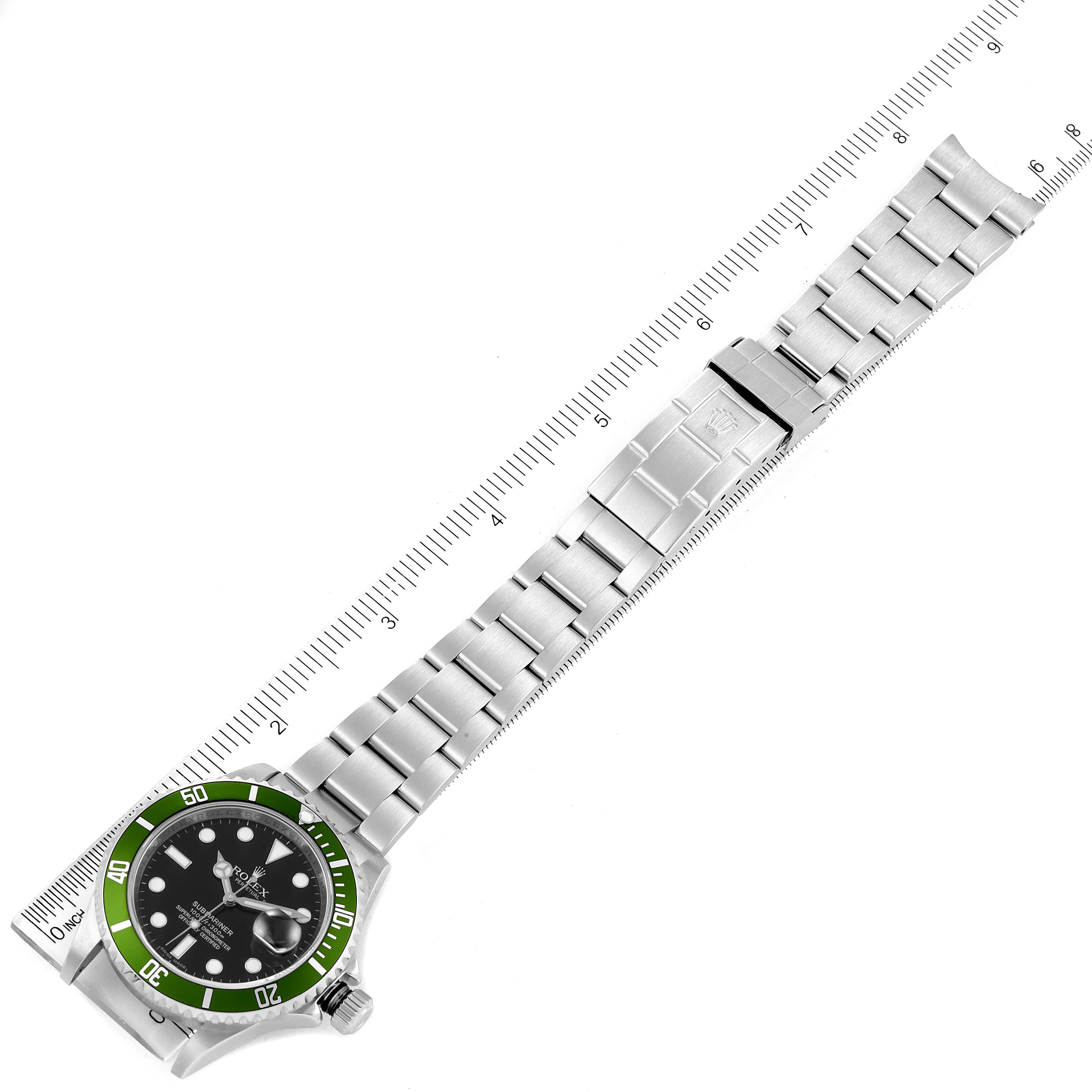 The image shows an overhead view of a Rolex Submariner 16610LV Men's Stainless Steel Black Dial 16610LV Men's Stainless Steel Black Dial watch with a stainless steel bracelet and green bezel, measured against a ruler.
