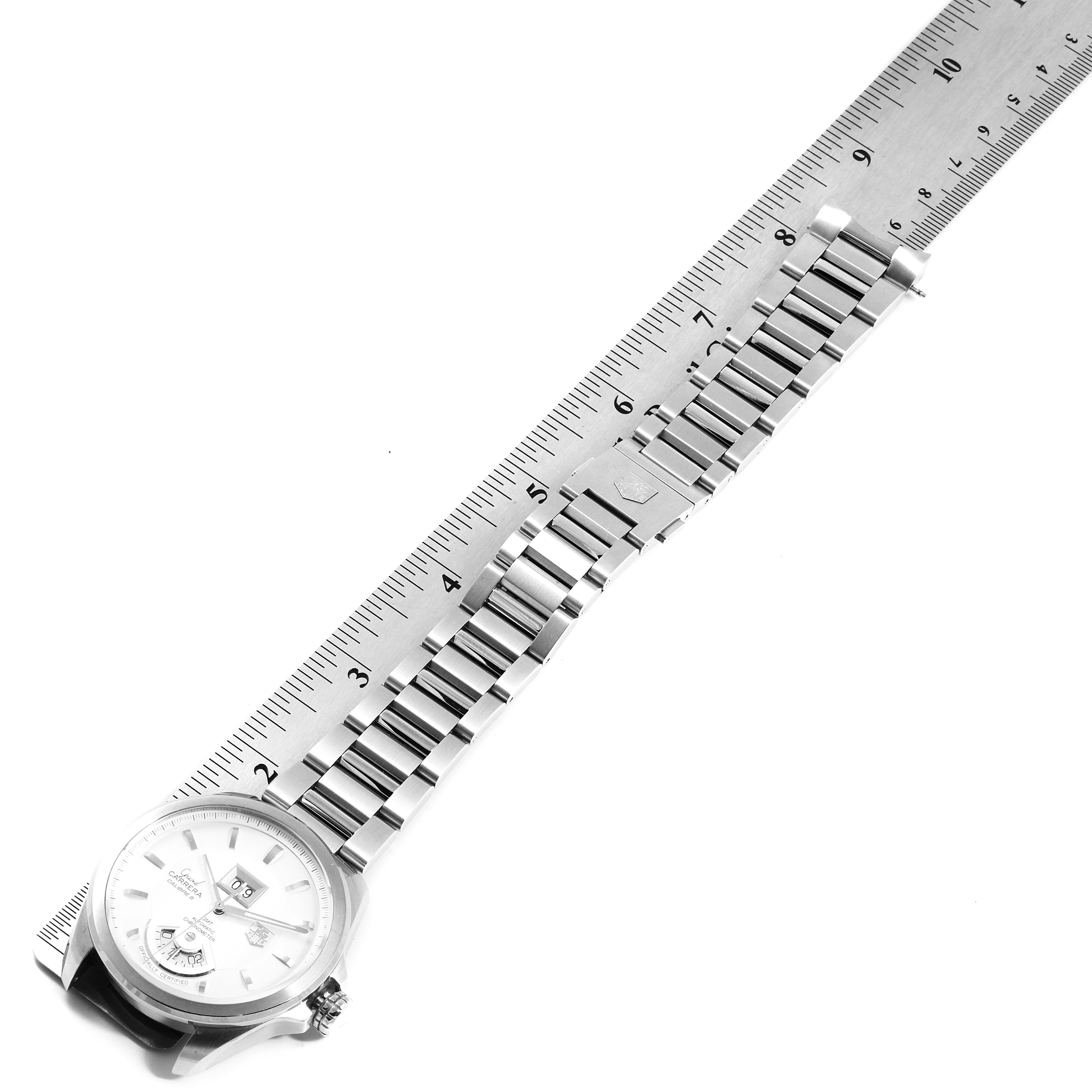 The image shows a Tag Heuer Carrera WAV5112.BA0901 Men's Stainless Steel Silver Dial WAV5112.BA0901 Men's Stainless Steel Silver Dial watch positioned next to a ruler, highlighting its metal strap and dial.