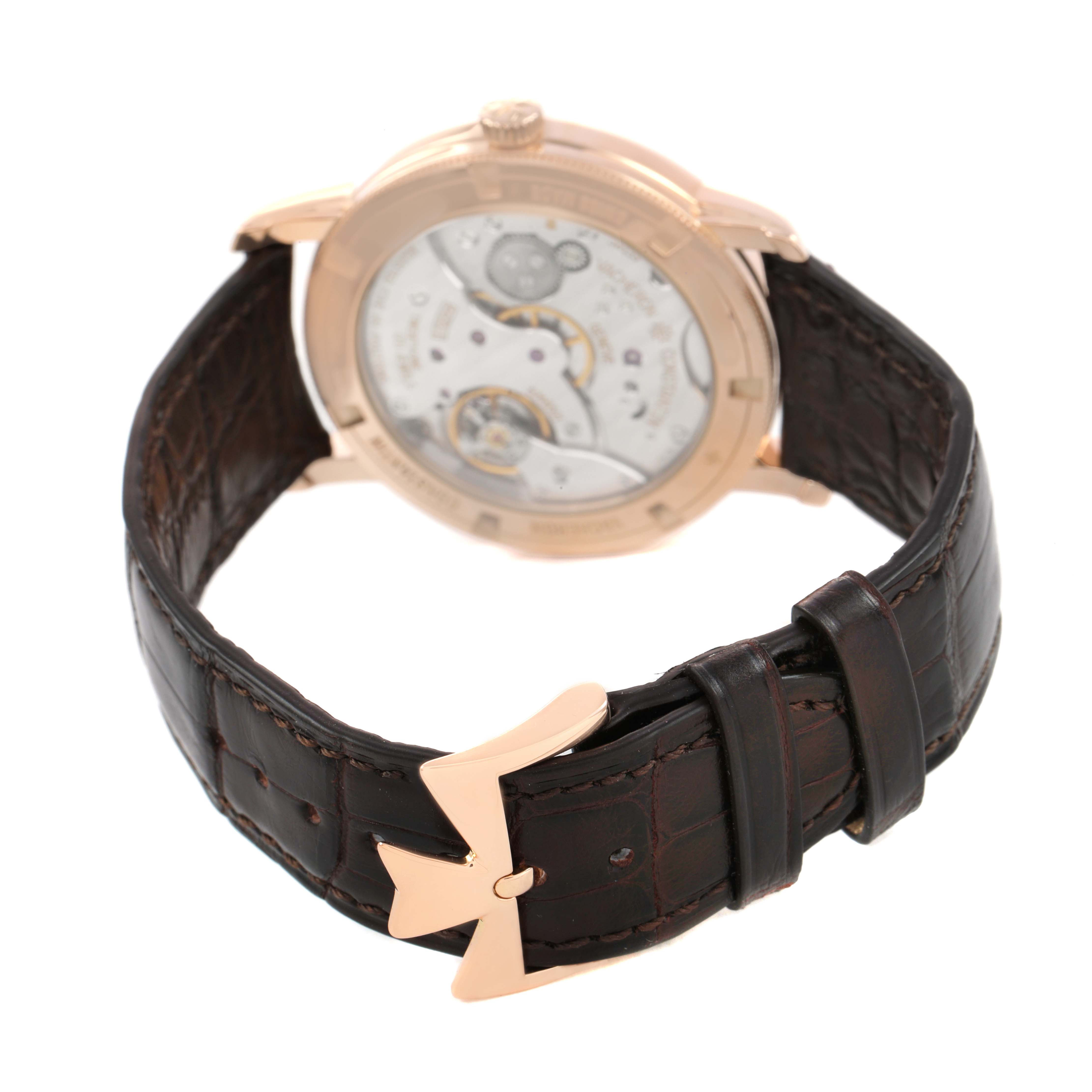 The Vacheron Constantin Traditionnelle 82172 Men's Rose Gold Silver Dial watch is shown from the rear, displaying its transparent case back and brown leather strap with a branded clasp.