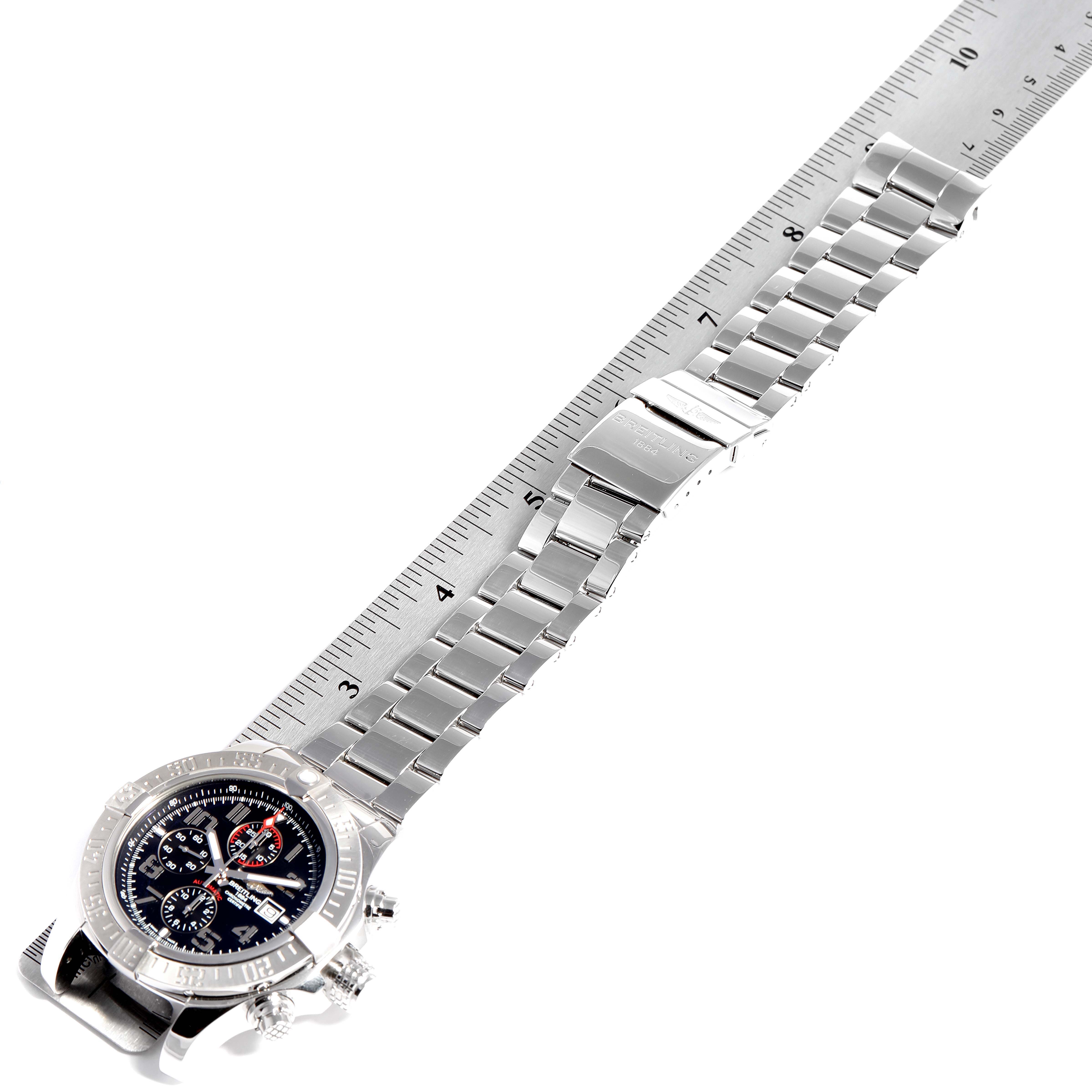 The image shows a Breitling Avenger A13371 Men
s Stainless Steel Black Dial A13371 Men
s Stainless Steel Black Dial watch from a top-down angle, highlighting the watch face and metal bracelet against a ruler.