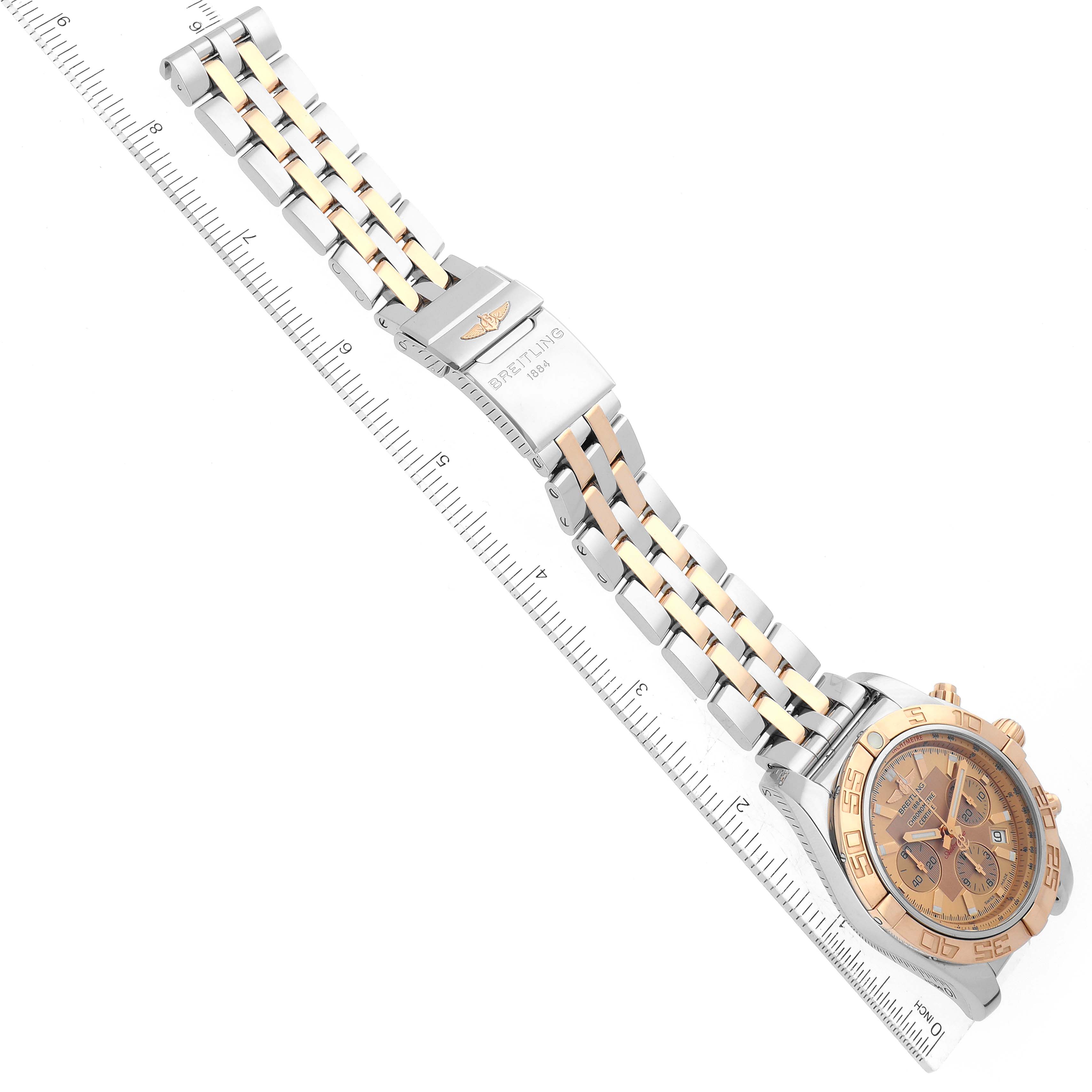 This image shows the Breitling Chronomat CB011012/B957 Men's Stainless Steel Champagne Dial CB011012/B957 Men's Stainless Steel Champagne Dial watch laid flat, displaying the face, bezel, and metal bracelet alongside a ruler.