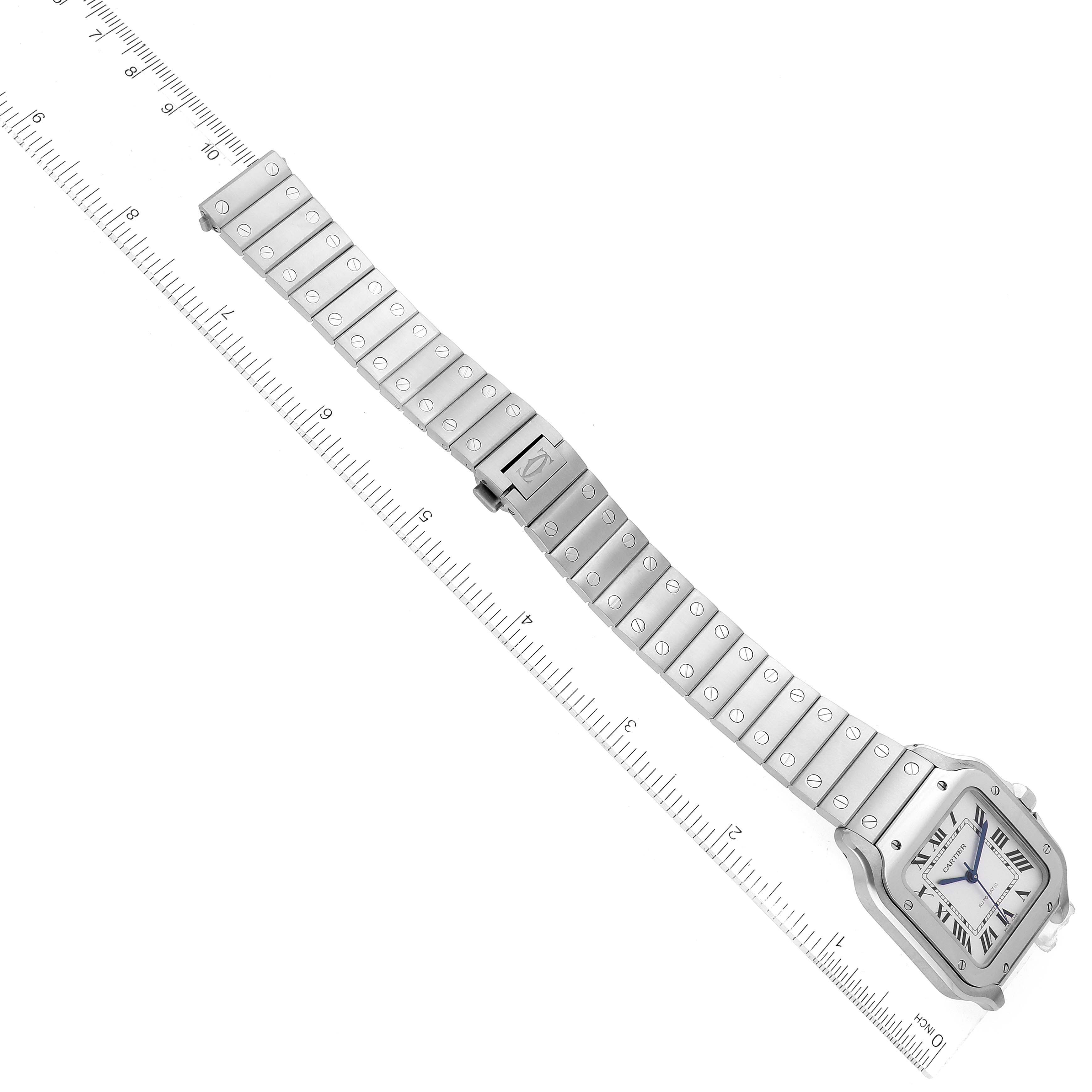 This image shows the Cartier Santos WSSA0029 Men
s Stainless Steel Silver Dial WSSA0029 Men
s Stainless Steel Silver Dial watch laid flat with a full view of the watch face and metal bracelet, beside a ruler for size reference.