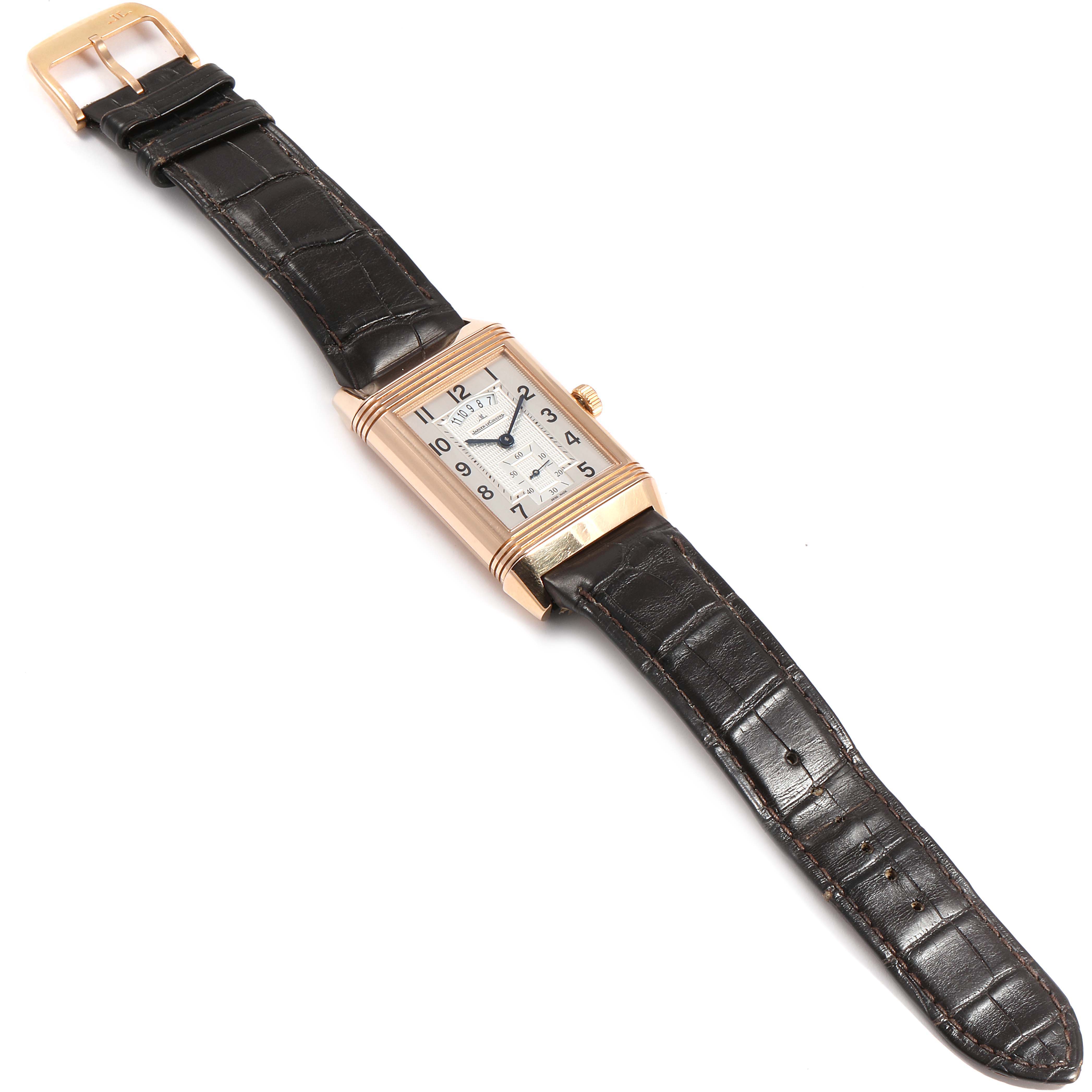 The image shows a Jaeger-LeCoultre Reverso watch from a top-down angle, highlighting the rectangular face and leather strap.