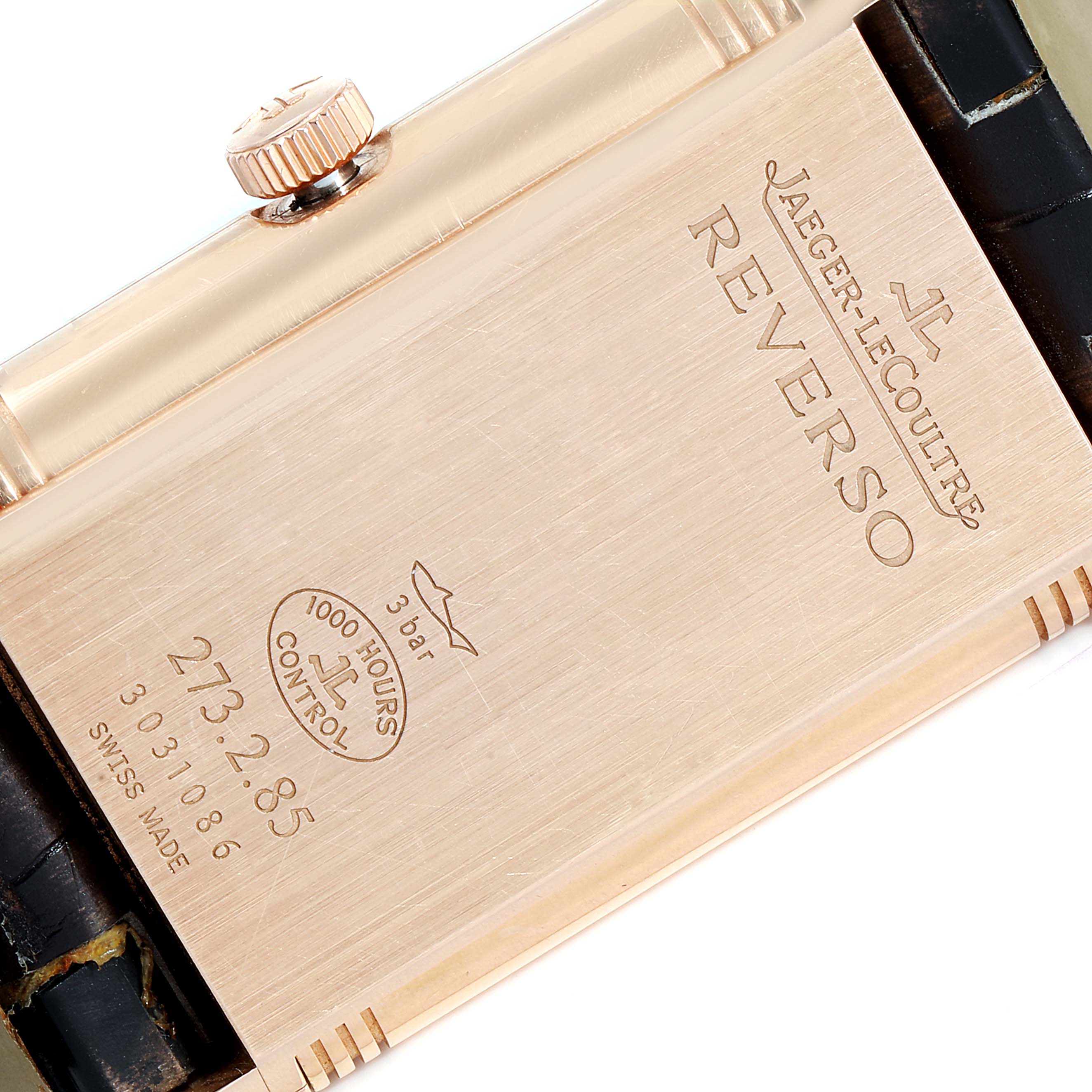 This image shows the back casing and crown of a Jaeger-LeCoultre Reverso watch, including engravings and part of the strap.