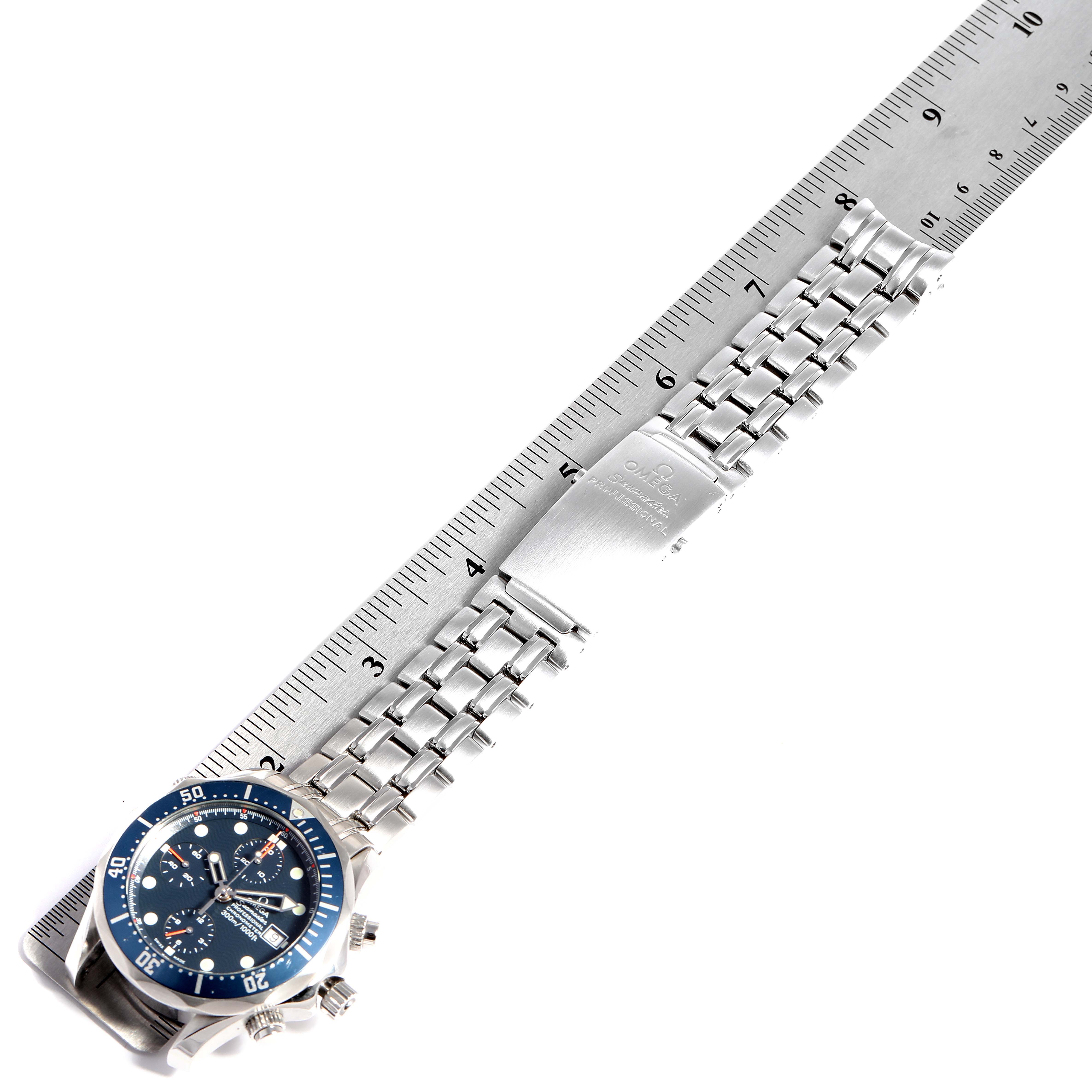 This image shows an Omega Seamaster 2599.80.00 Men
s Stainless Steel Blue Dial 2599.80.00 Men
s Stainless Steel Blue Dial watch lying flat on a ruler, displaying its face, bezel, and metal bracelet with clasp.