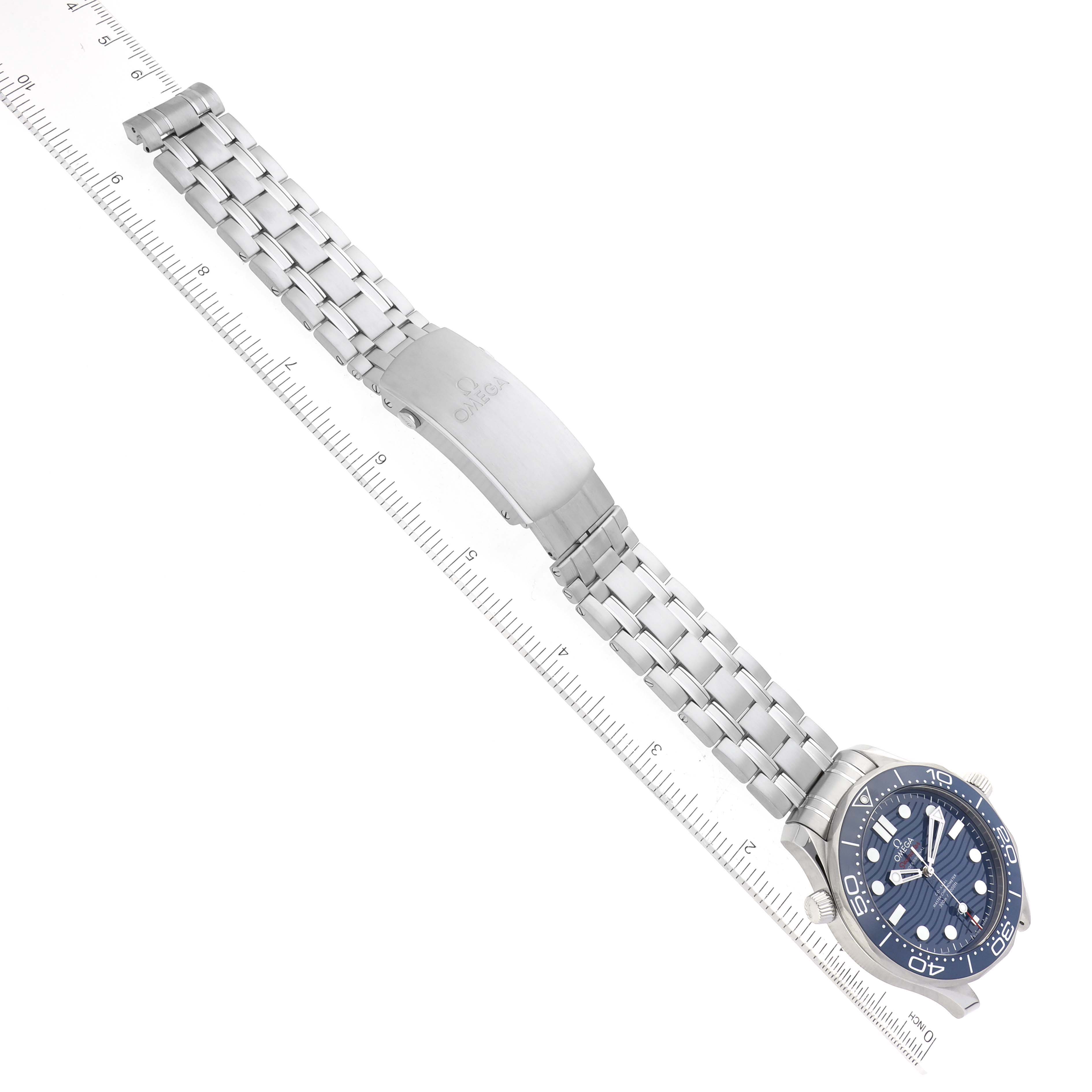 The image shows an Omega Seamaster 210.30.42.20.03.001 Men
s Stainless Steel Blue Dial 210.30.42.20.03.001 Men
s Stainless Steel Blue Dial watch placed diagonally, with emphasis on the strap and clasp alongside a ruler for size reference.