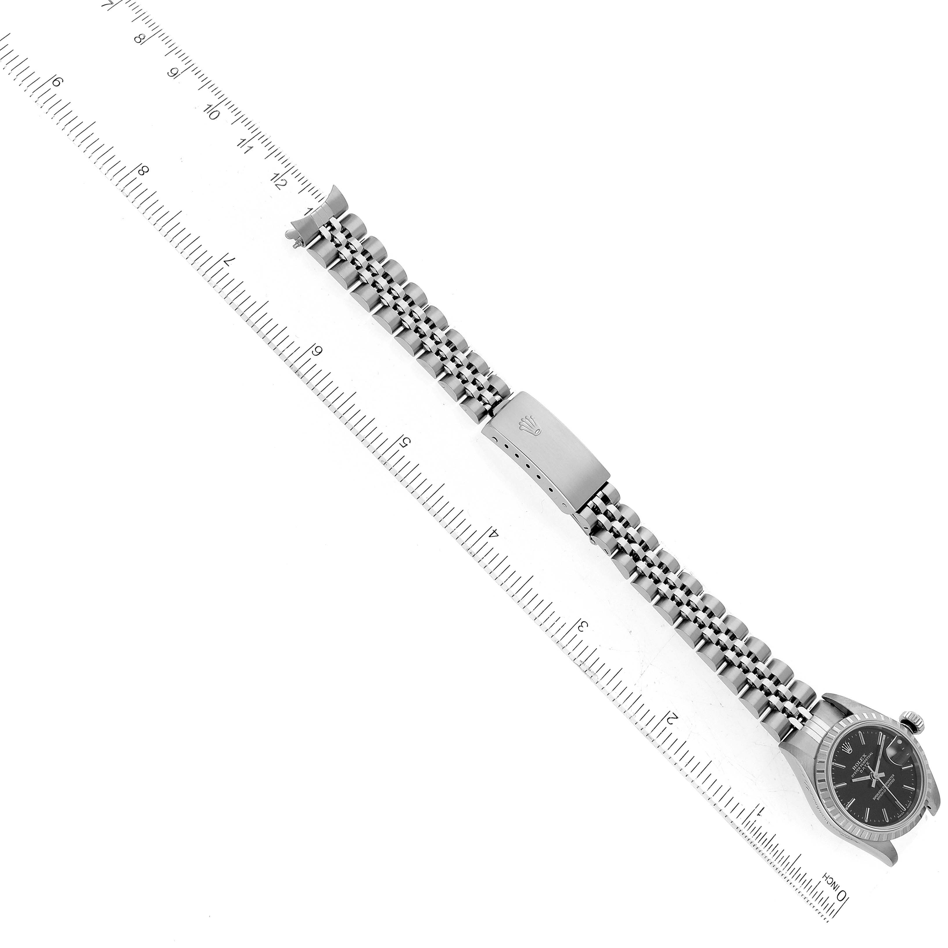 The Rolex Date 79240 Women's Stainless Steel Black Dial 79240 Women's Stainless Steel Black Dial model watch is shown from an overhead angle with a visible bracelet and clasp, next to a ruler.