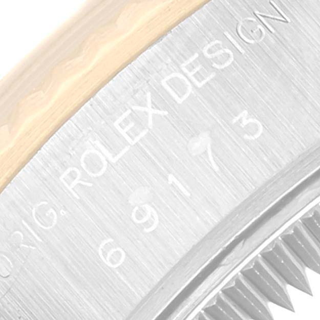 The image shows an angled close-up of the side of a Rolex Datejust 69173 Women's Steel and Gold (two tone) Black Dial 69173 Women's Steel and Gold (two tone) Black Dial model, displaying its model number and "Rolex Design" engraving.