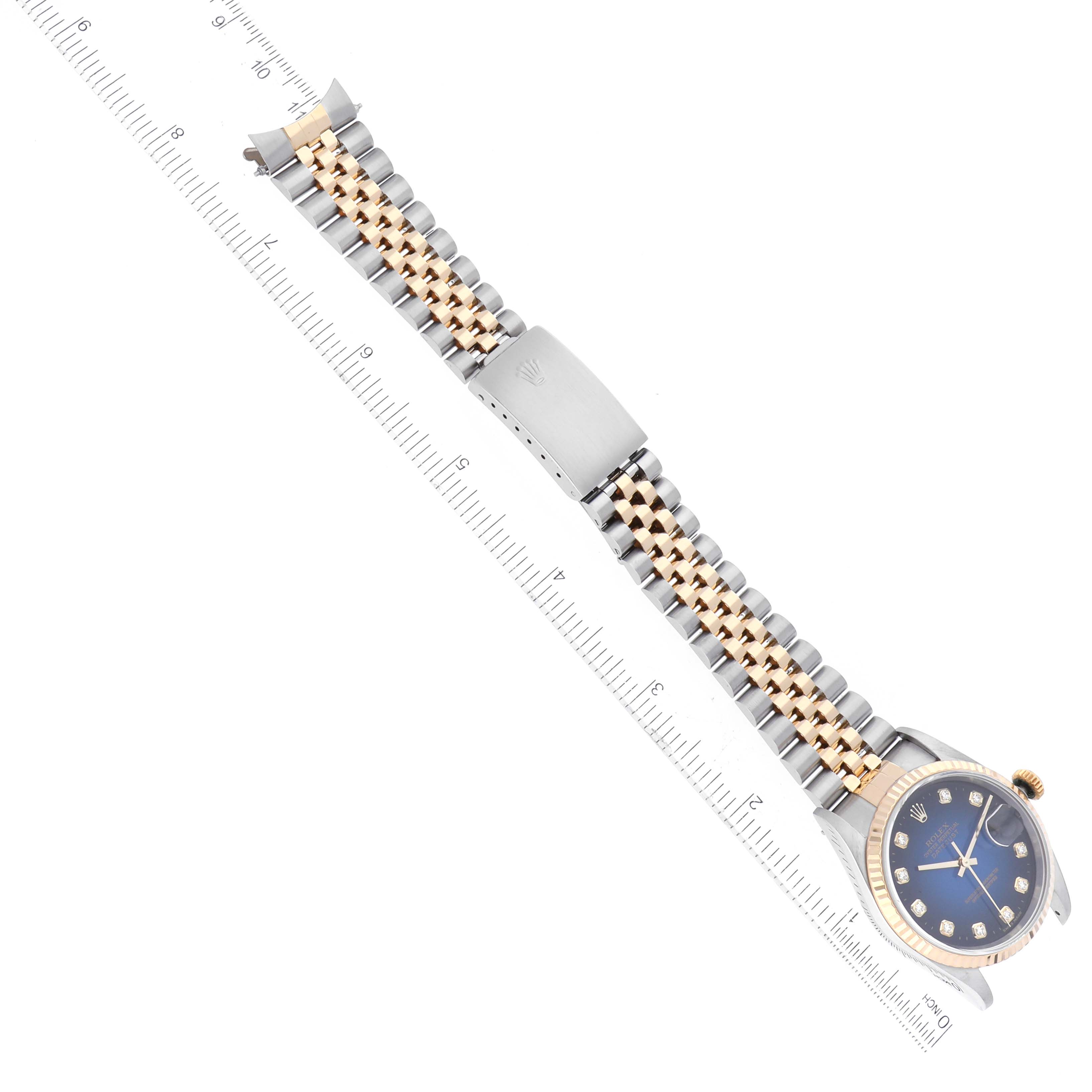 The Rolex Datejust 16233 Men's Steel and Gold (two tone) Blue Dial 16233 Men's Steel and Gold (two tone) Blue Dial watch is shown from an angled top-down view, highlighting its face, bezel, and Jubilee bracelet with a ruler.