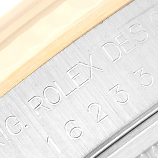 The image shows a close-up of the engraved text "ROLEX" on the bezel of a Rolex Datejust 16233 Men's Steel and Gold (two tone) Blue Dial 16233 Men's Steel and Gold (two tone) Blue Dial watch.