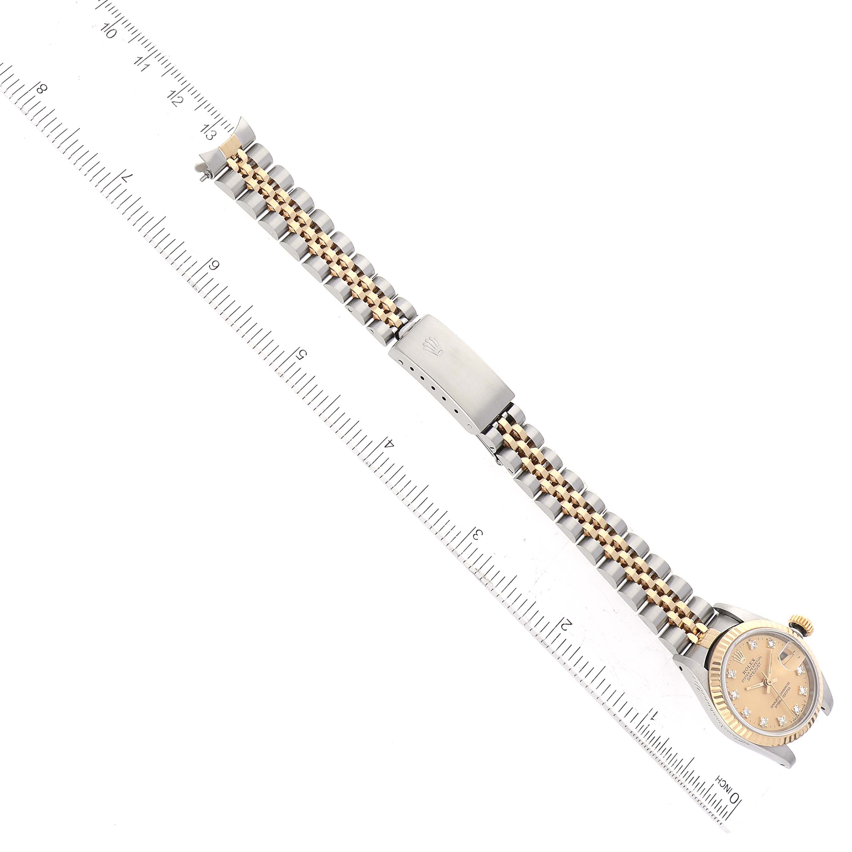 The Rolex Datejust 69173 Women's Steel and Gold (two tone) Champagne Dial 69173 Women's Steel and Gold (two tone) Champagne Dial watch is shown from an overhead angle, displaying its bracelet, clasp, and dial placed next to a ruler.