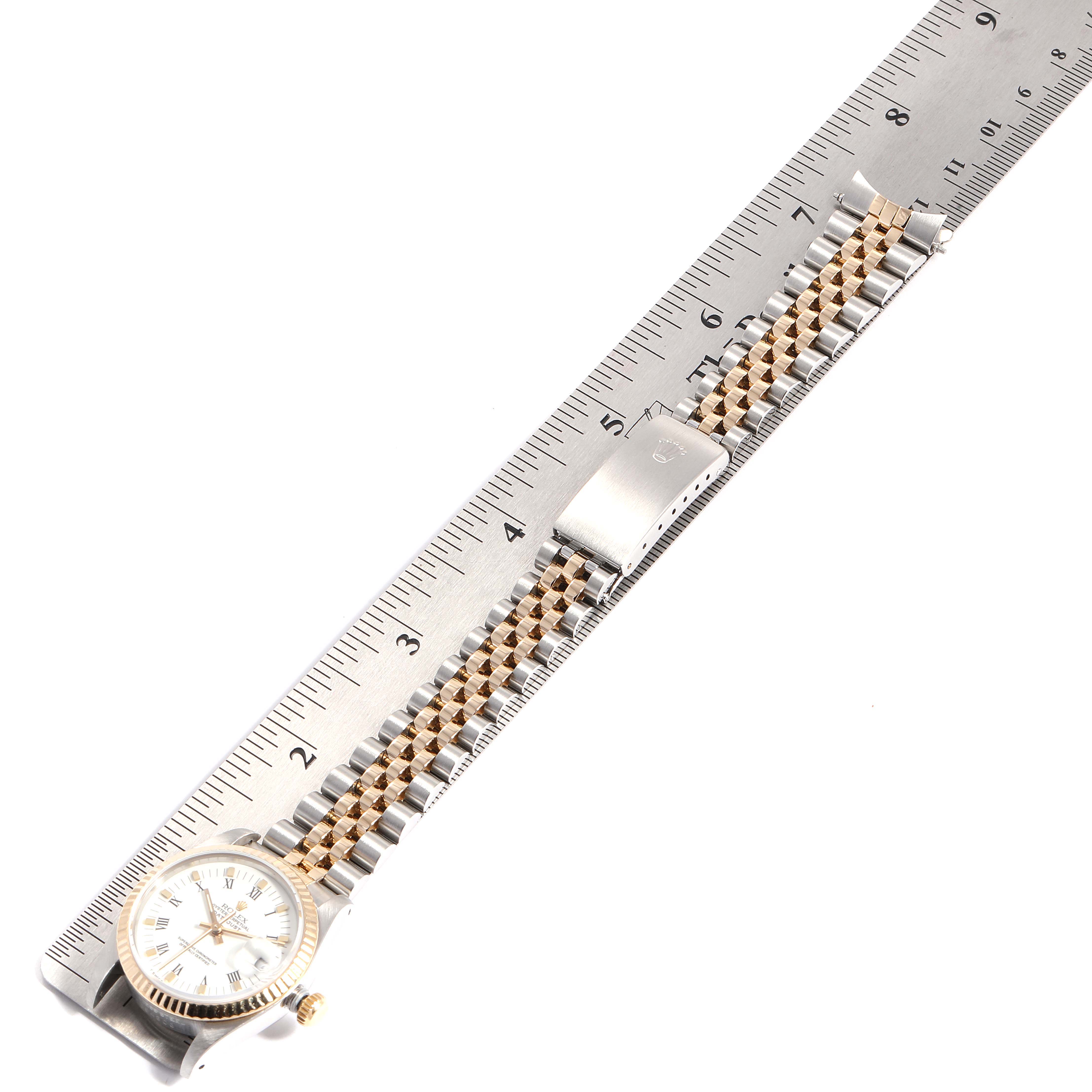 The image shows a Mid-Size Rolex watch laid flat with its bracelet extended alongside a ruler for measurement.