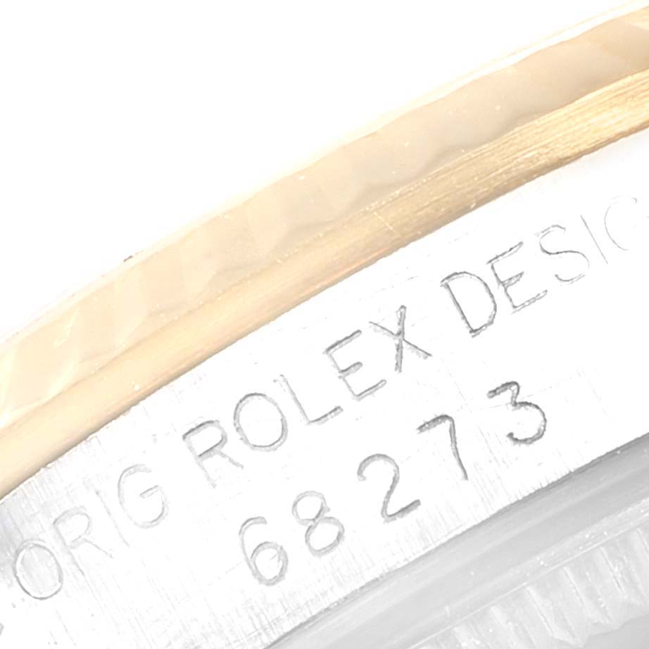 The image shows a close-up of a Rolex Mid-Size 68273 Women
s Steel and Gold (two tone) White Dial 68273 Women
s Steel and Gold (two tone) White Dial model, featuring the engraved model number "68273" and part of the bezel.