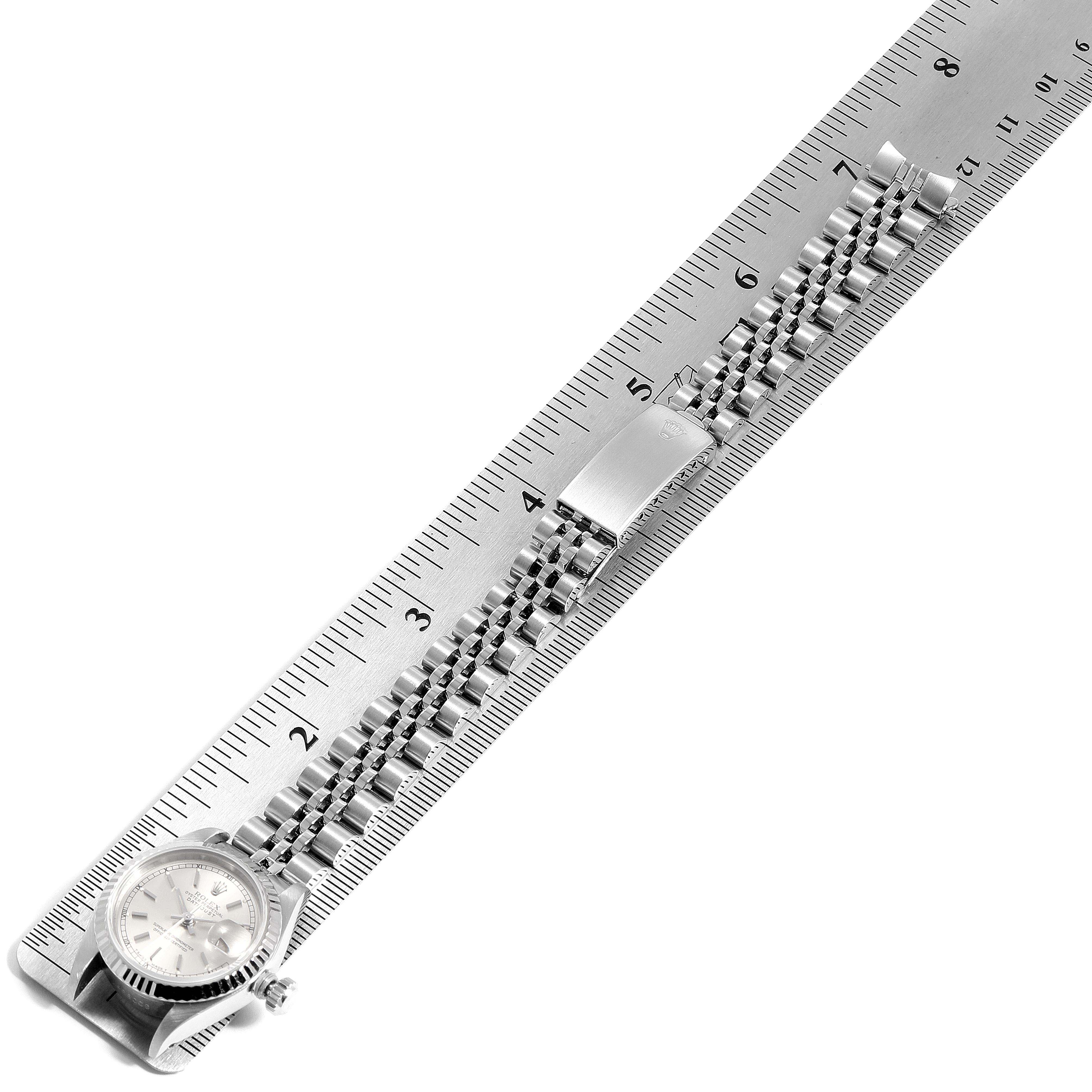 This image shows a side angle of a Rolex Datejust 69174 Women's Stainless Steel Silver Dial 69174 Women's Stainless Steel Silver Dial watch with a stainless steel bracelet laid alongside a ruler.