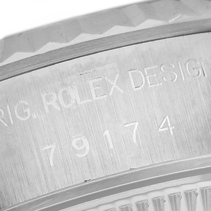 The image shows a close-up of the engraved Rolex Datejust 79174 Women's Stainless Steel Silver Dial 79174 Women's Stainless Steel Silver Dial model number and "ROLEX DESIGN" text on the watch case.