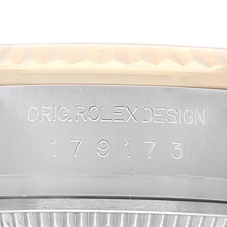 This is a close-up of the side of a Rolex Datejust 179173 Women's Steel and Gold (two tone) Blue Dial 179173 Women's Steel and Gold (two tone) Blue Dial model watch, showing the engraved text and a portion of the bezel.