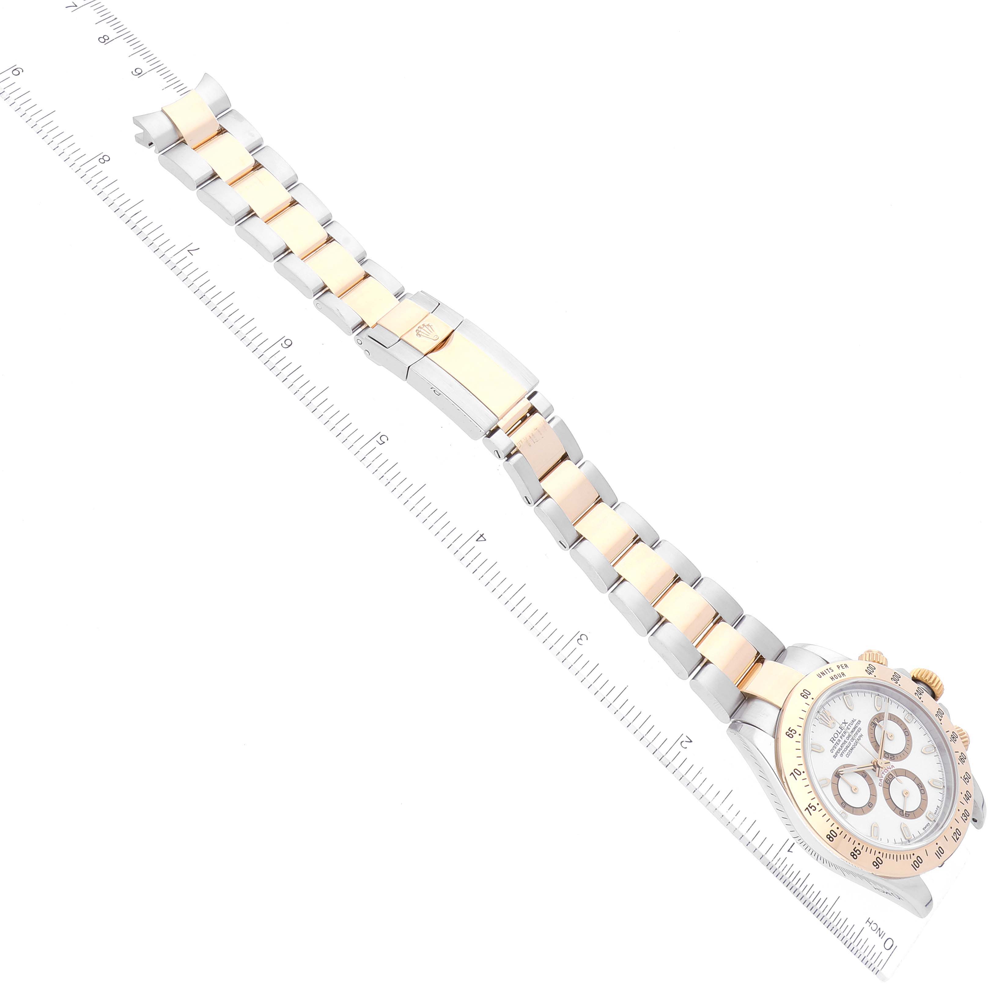 The image shows an overhead shot of a Rolex Daytona 116523 Men
s Steel and Gold (two tone) White Dial 116523 Men
s Steel and Gold (two tone) White Dial watch, highlighting the full bracelet, clasp, and face alongside a ruler.