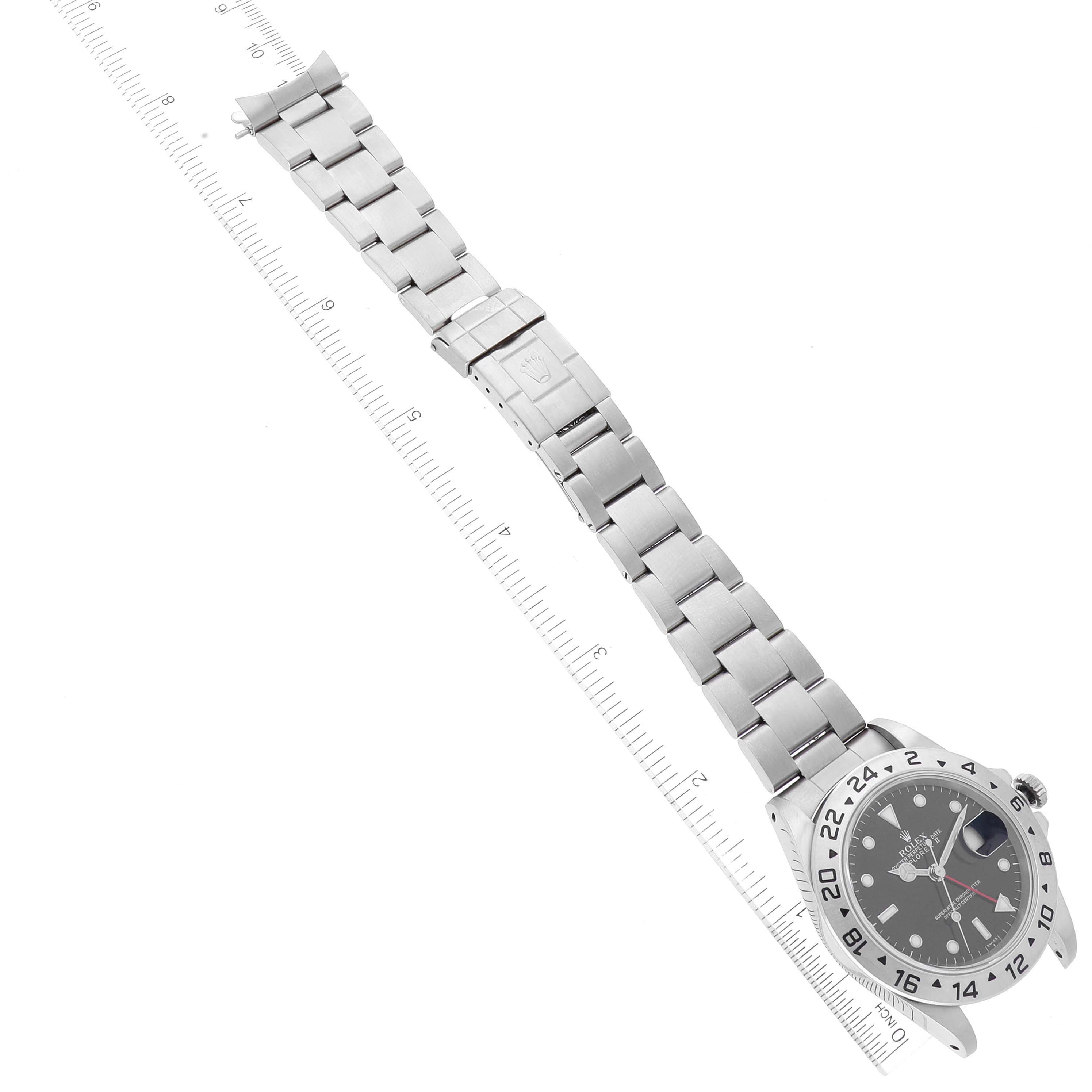 The image shows a top view of a Rolex Explorer 16570 Men
s Stainless Steel Black Dial 16570 Men
s Stainless Steel Black Dial watch, featuring its stainless steel bracelet and face with a measuring ruler underneath.