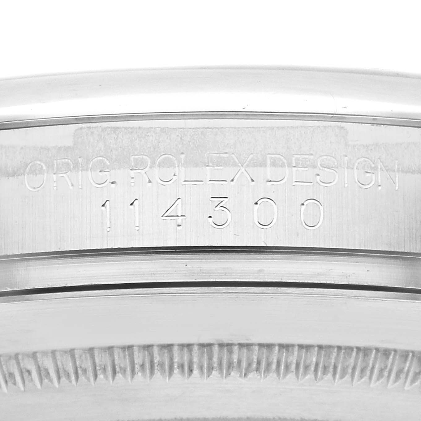 This image shows a close-up of the engraved caseback for the Rolex Oyster Perpetual 114300 Men's Stainless Steel Grey Dial 114300 Men's Stainless Steel Grey Dial model, displaying "Orig Rolex Design 114300."