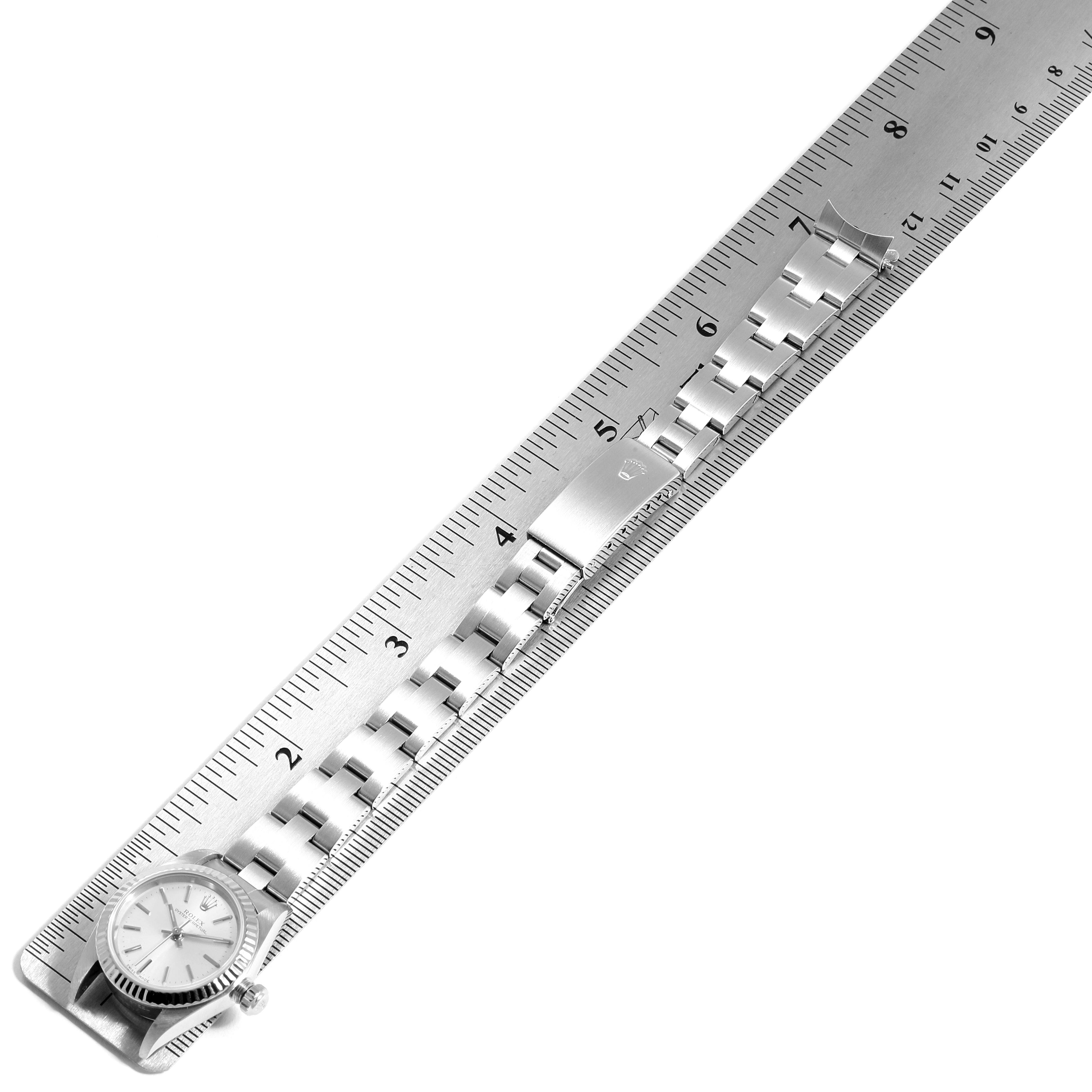 The image shows a Rolex Oyster Perpetual 76094 Women's Stainless Steel Silver Dial 76094 Women's Stainless Steel Silver Dial watch from a top-down angle, with a stainless steel band and a clasp, measured against a ruler.