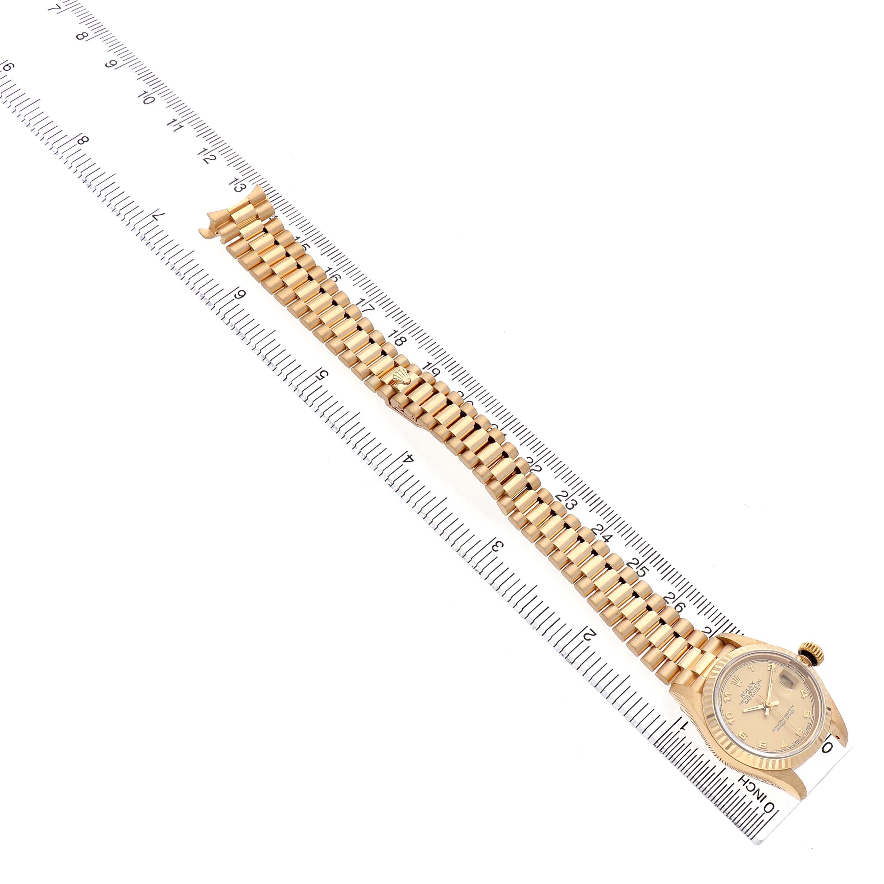 The Rolex President 69178 Women's Yellow Gold Champagne Dial model watch is shown from an overhead angle with its bracelet laid along a ruler.