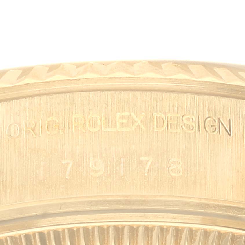 This is a close-up shot of the side of a Rolex President 79178 Women
s Yellow Gold Champagne Dial 79178 Women
s Yellow Gold Champagne Dial watch, showing "ORIG. ROLEX DESIGN" engraved on the bezel.
