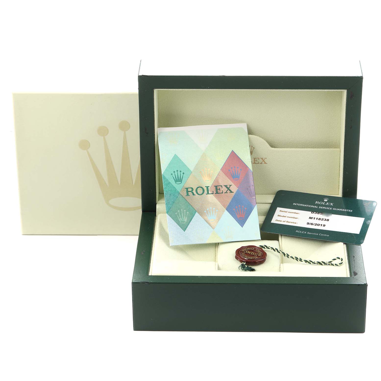 The Rolex President 118238 Men's Yellow Gold White Dial 118238 Men's Yellow Gold White Dial watch box is shown open, displaying booklets, a warranty card, and a tag.