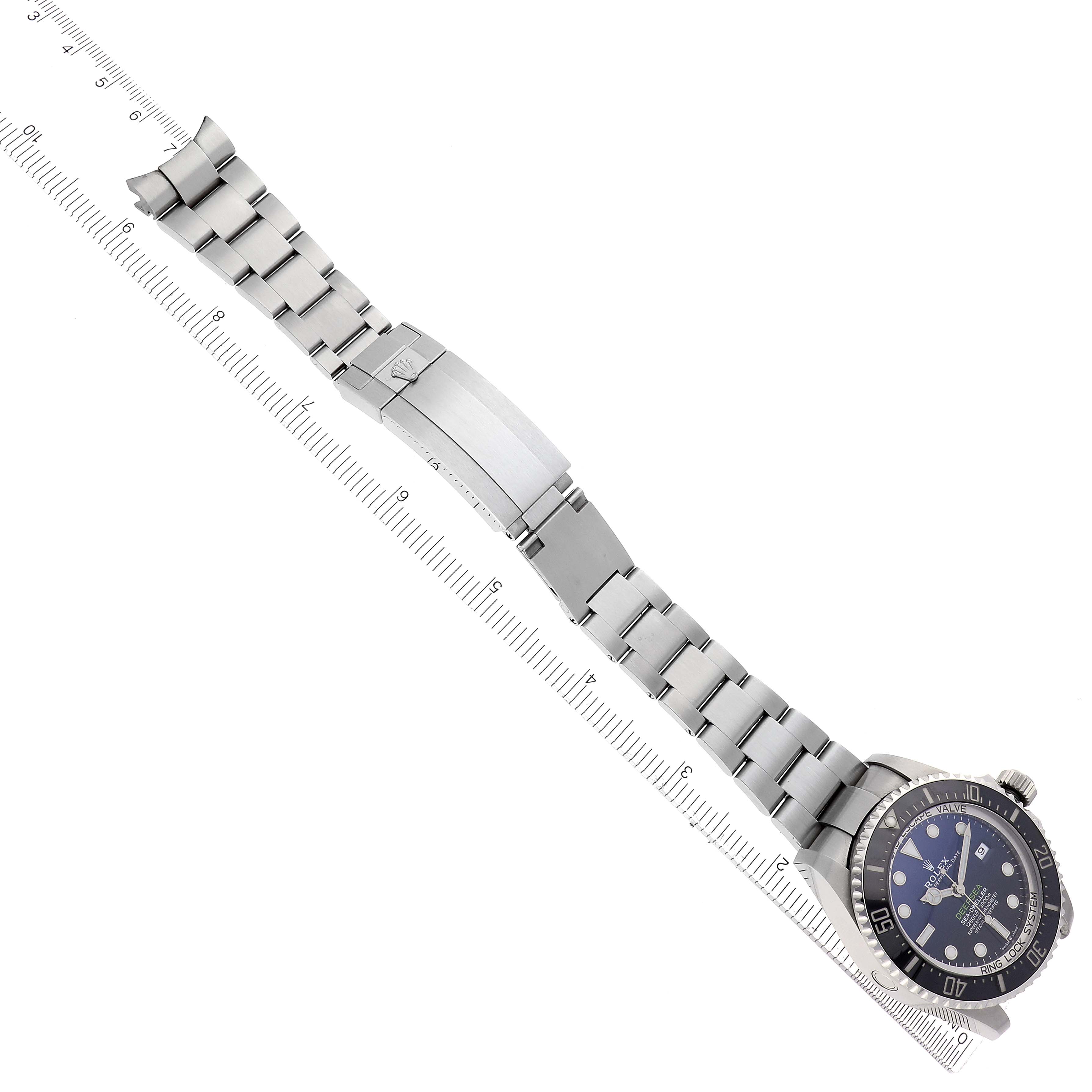 The Rolex Sea-Dweller 126660 Men's Stainless Steel Blue Dial 126660 Men's Stainless Steel Blue Dial watch is shown with a side angle, displaying the bracelet, clasp, and face aligned with a measuring ruler.