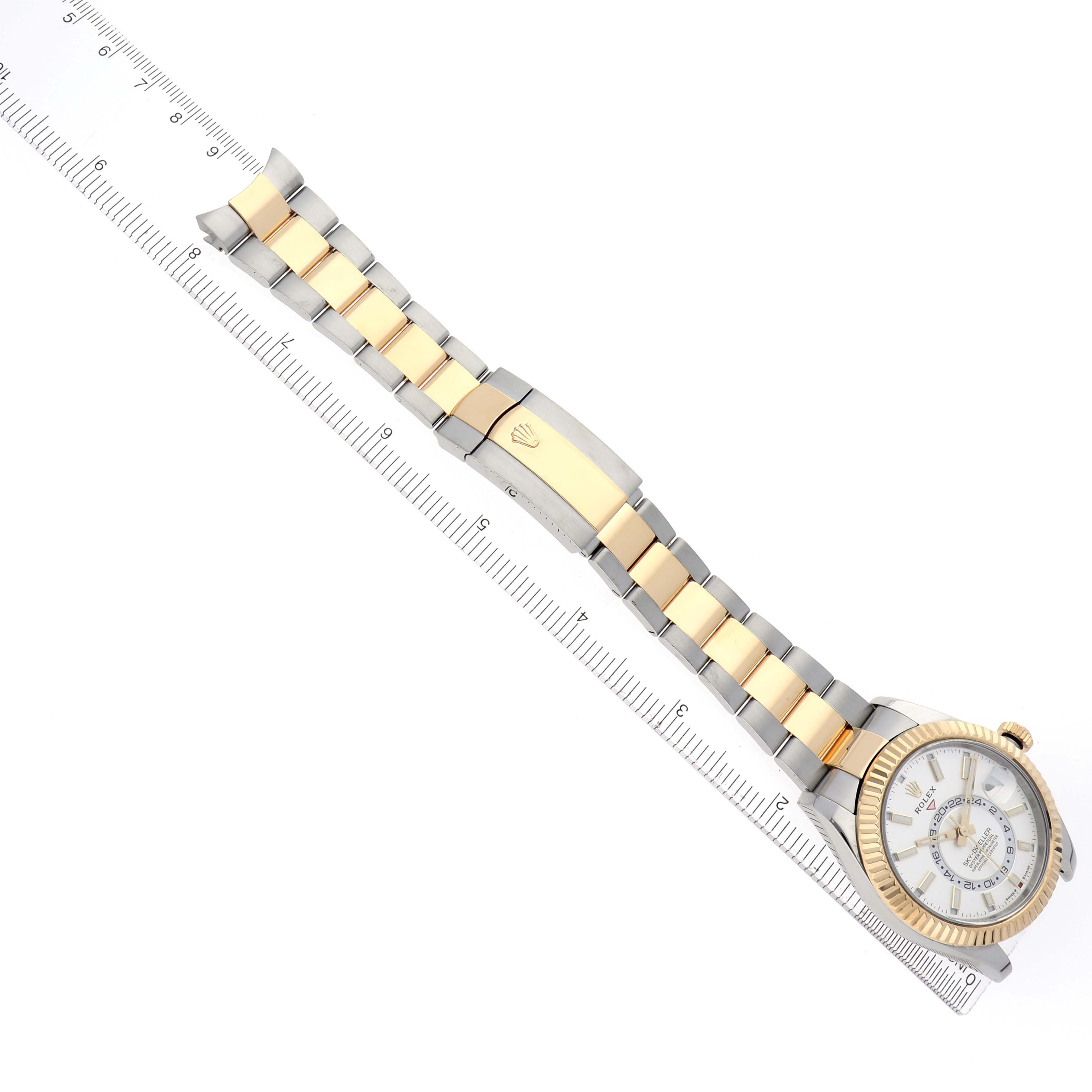 The Rolex Sky-Dweller 336933 Men's Steel and Gold (two tone) Silver Dial 336933 Men's Steel and Gold (two tone) Silver Dial watch is shown from a top view, highlighting the bracelet, clasp, dial, and bezel alongside a ruler.