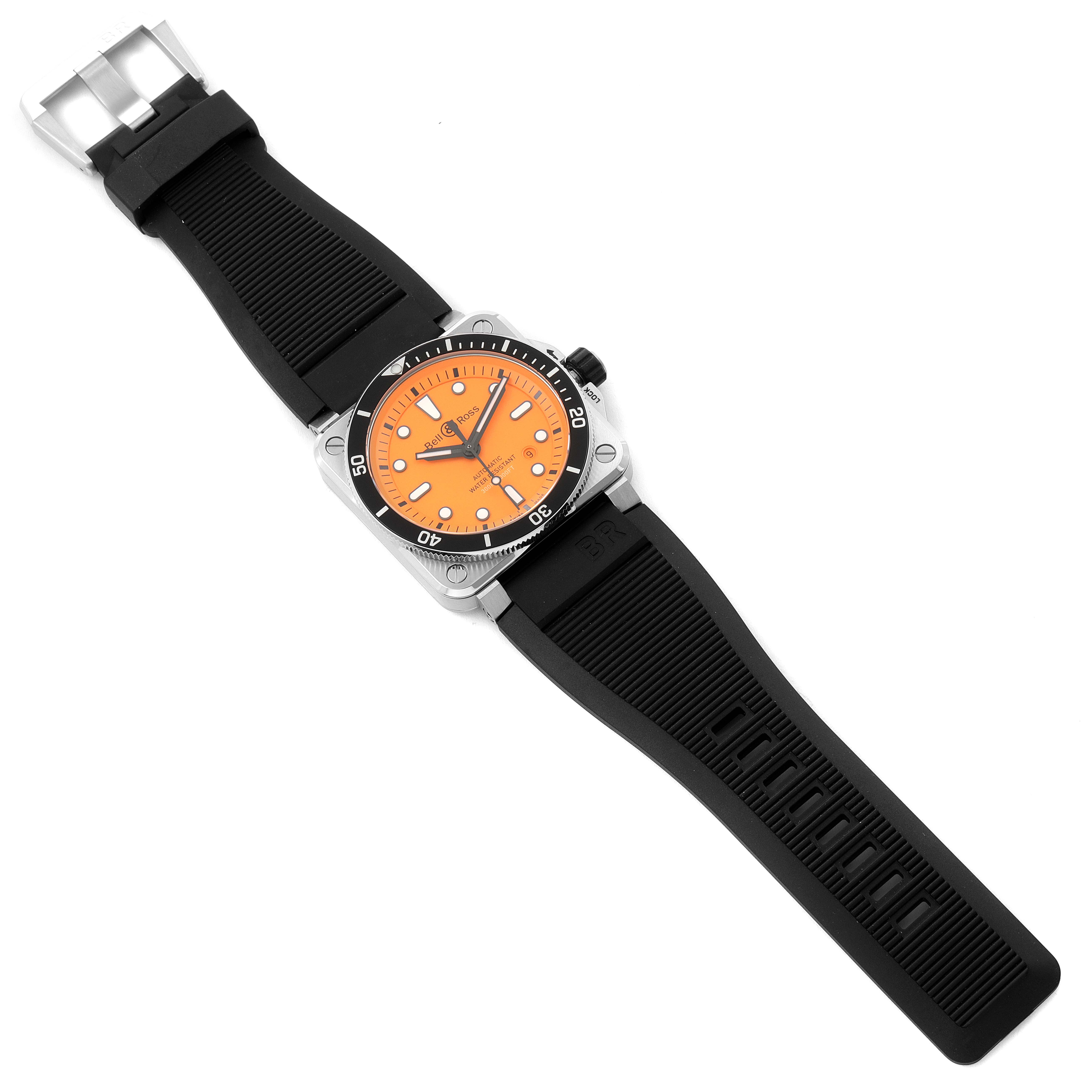 The image shows a Bell & Ross Diver model watch with an orange dial and a black rubber strap, viewed from above.