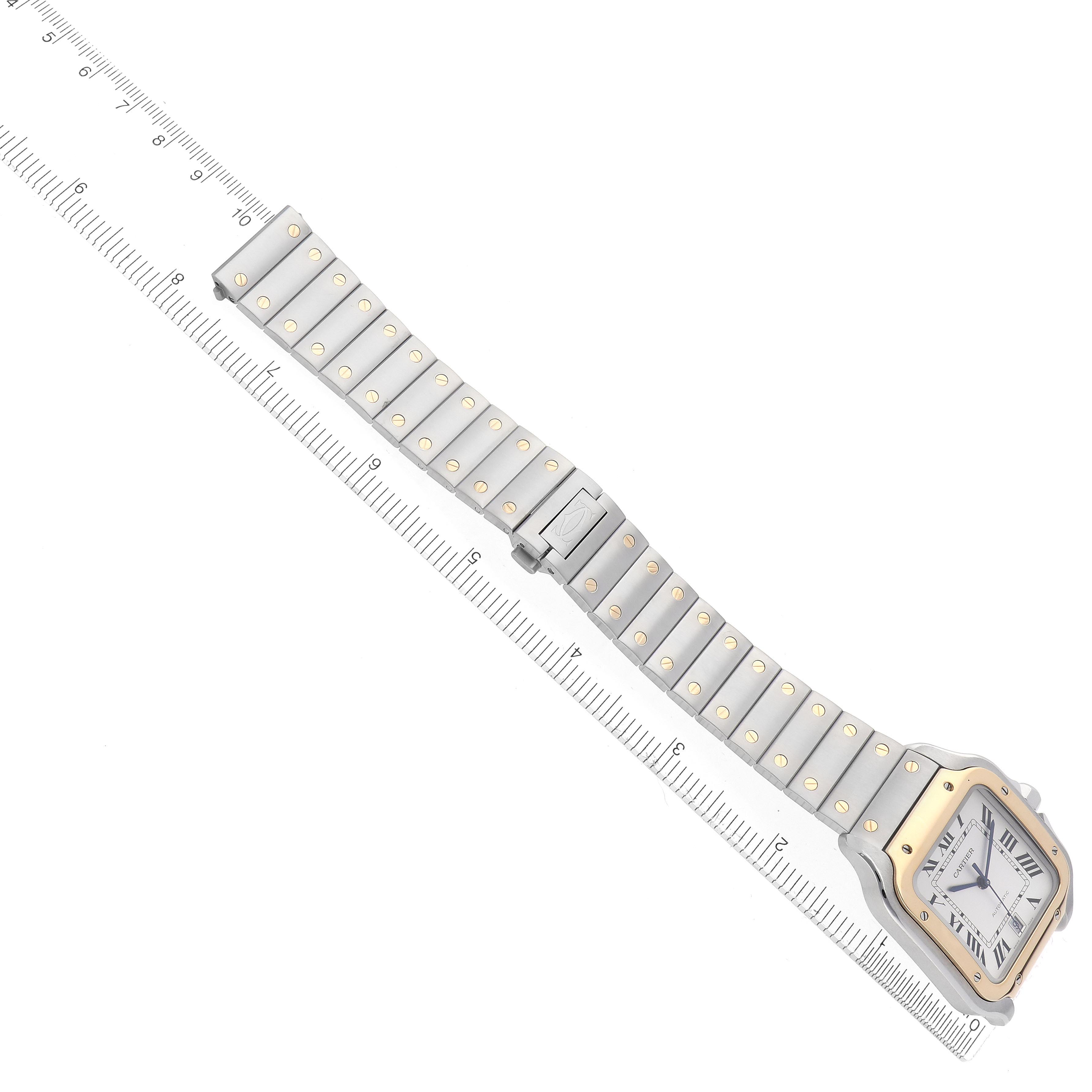 The Cartier Santos W2SA0009 Men's Steel and Gold (two tone) Silver Dial W2SA0009 Men's Steel and Gold (two tone) Silver Dial watch is shown from an overhead angle, featuring its face, bezel, and bracelet on a ruler for scale.