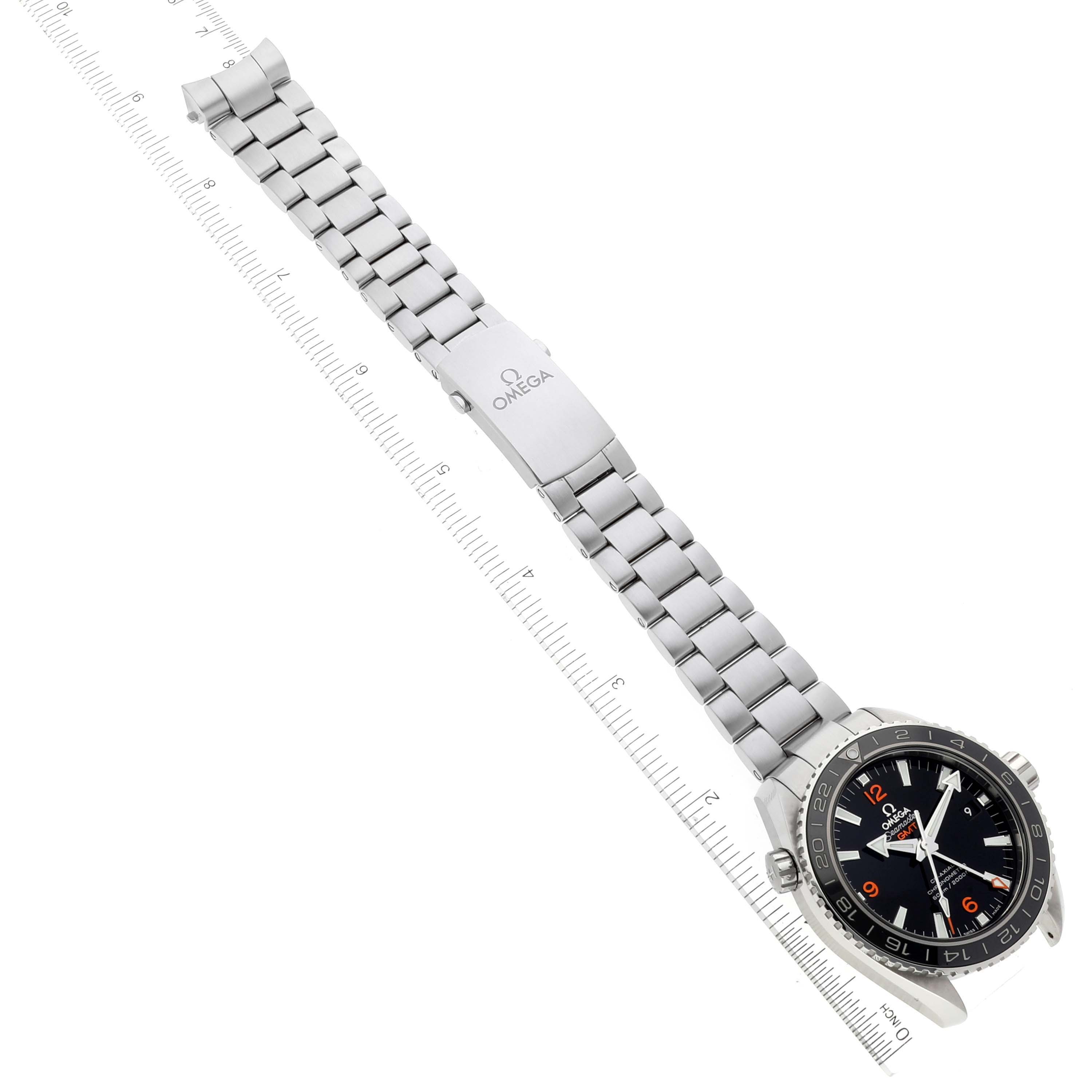 The image shows the Omega Planet Ocean 232.30.44.22.01.002 Men's Stainless Steel Black Dial 232.30.44.22.01.002 Men's Stainless Steel Black Dial watch with a metallic bracelet, displayed diagonally with a ruler aligned beside it.