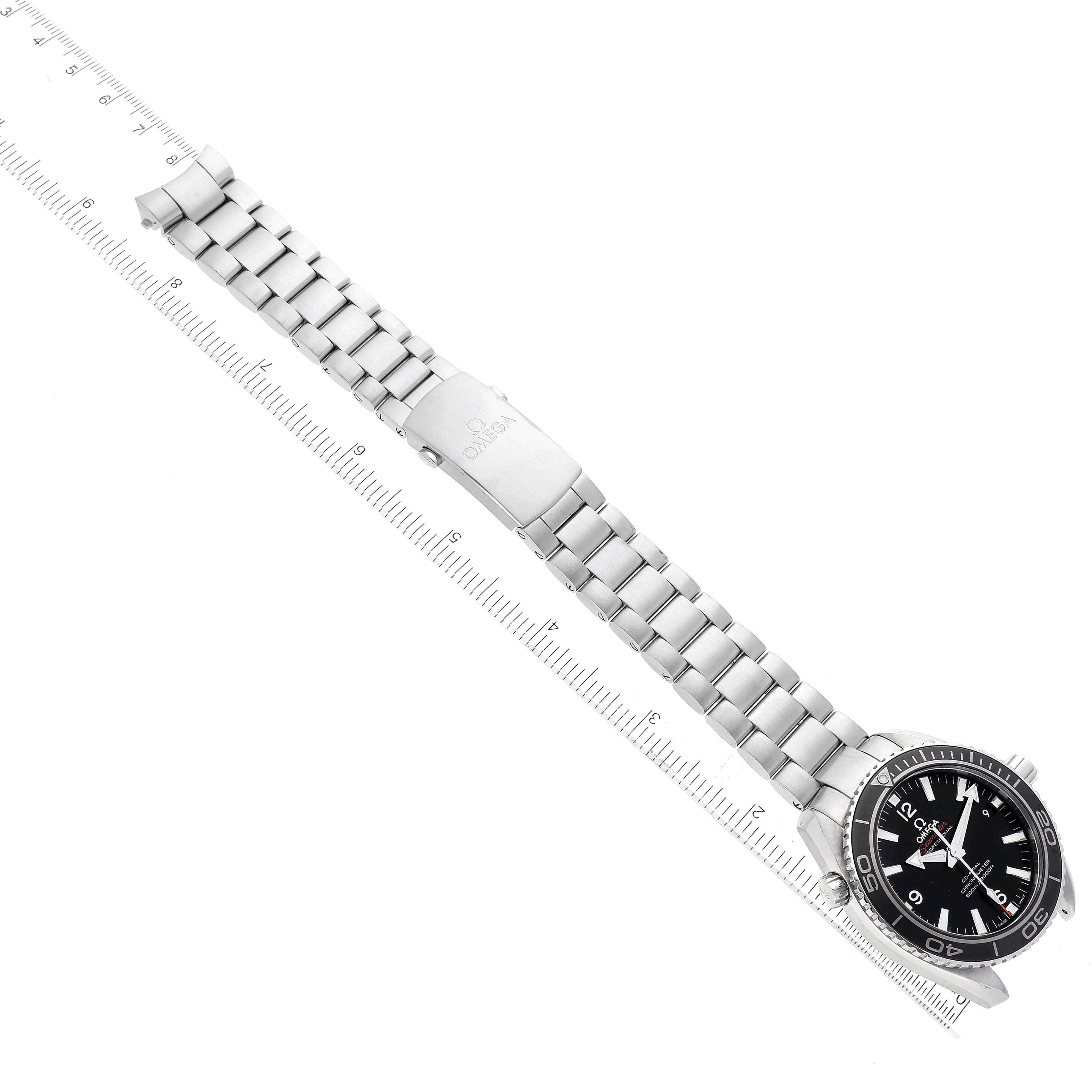 The image displays the Omega Planet Ocean 232.30.42.21.01.003 Men
s Stainless Steel Black Dial 232.30.42.21.01.003 Men
s Stainless Steel Black Dial watch laid out flat, showing its full bracelet and clasp, alongside a ruler for scale.
