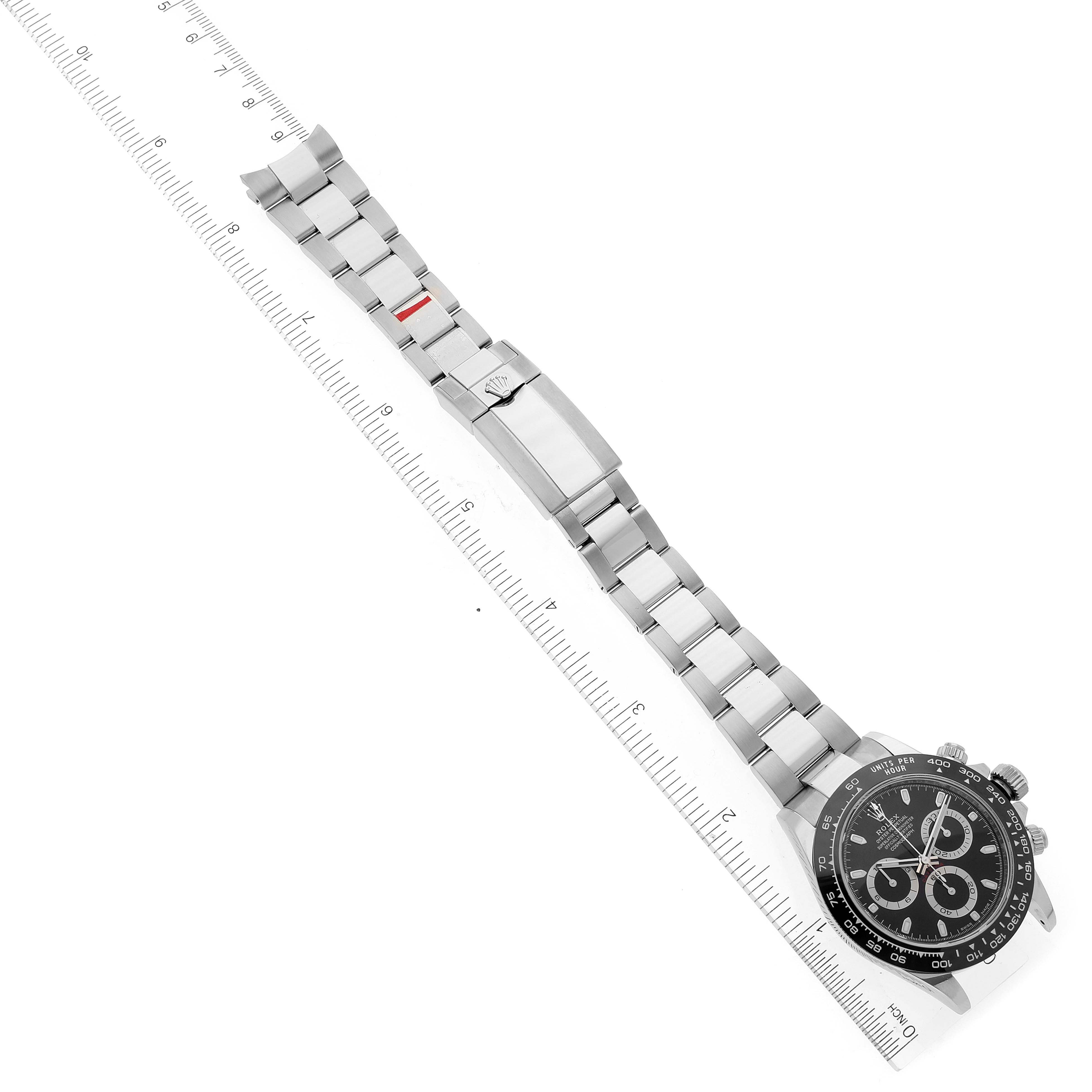 The image shows a top-down angle of a Rolex Daytona 116500 Men's Stainless Steel Black Dial 116500 Men's Stainless Steel Black Dial watch, displaying the face, bracelet, and deployment clasp alongside a ruler for scale.