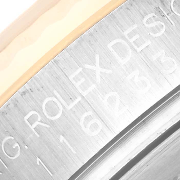 The image shows a close-up of the engraved side of a Rolex Datejust 116233 Men's Steel and Gold (two tone) Silver Dial 116233 Men's Steel and Gold (two tone) Silver Dial watch case.