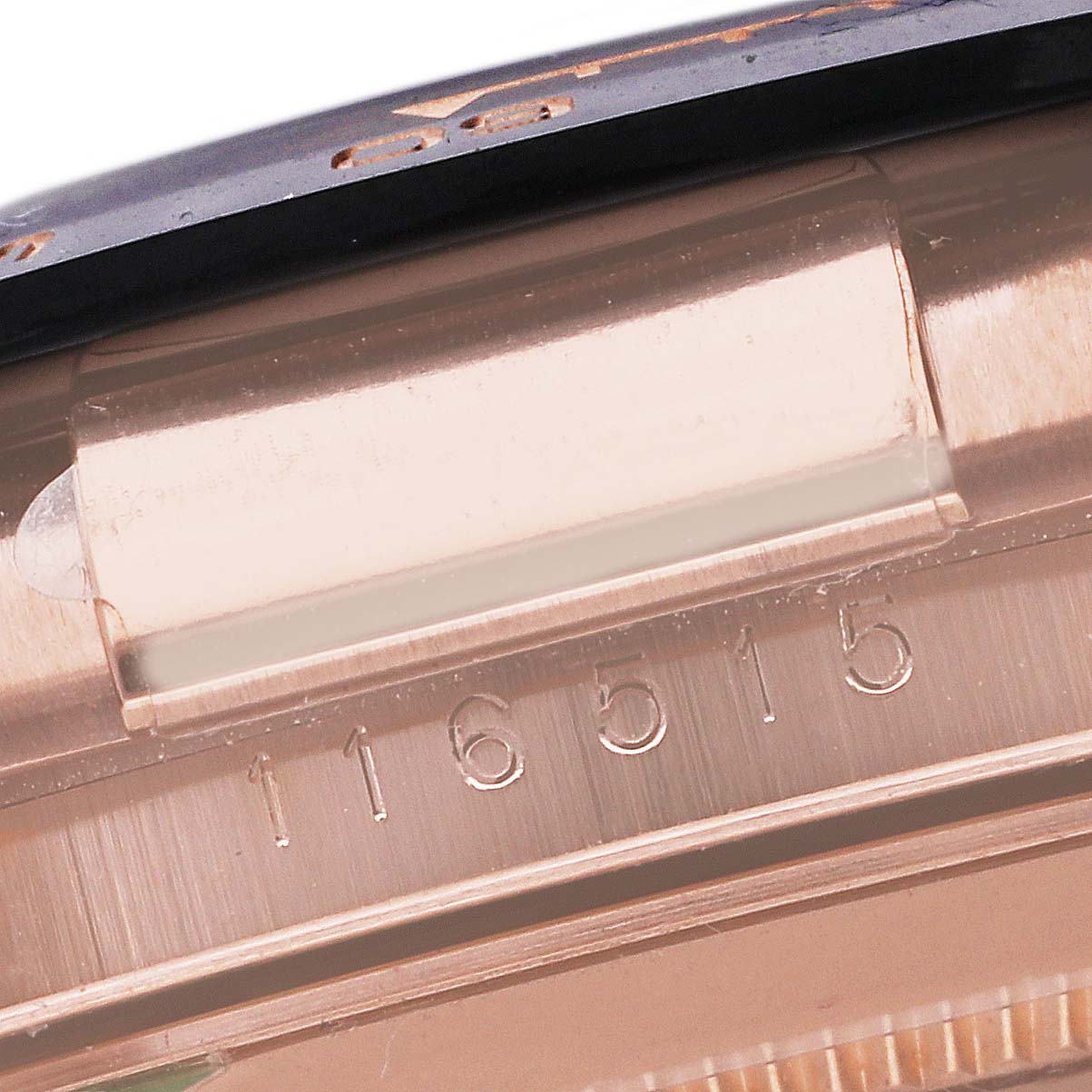 This close-up of a Rolex Daytona 116515 Men's Rose Gold Black Dial 116515 Men's Rose Gold Black Dial watch shows the model number engraved on the case and part of the bezel.