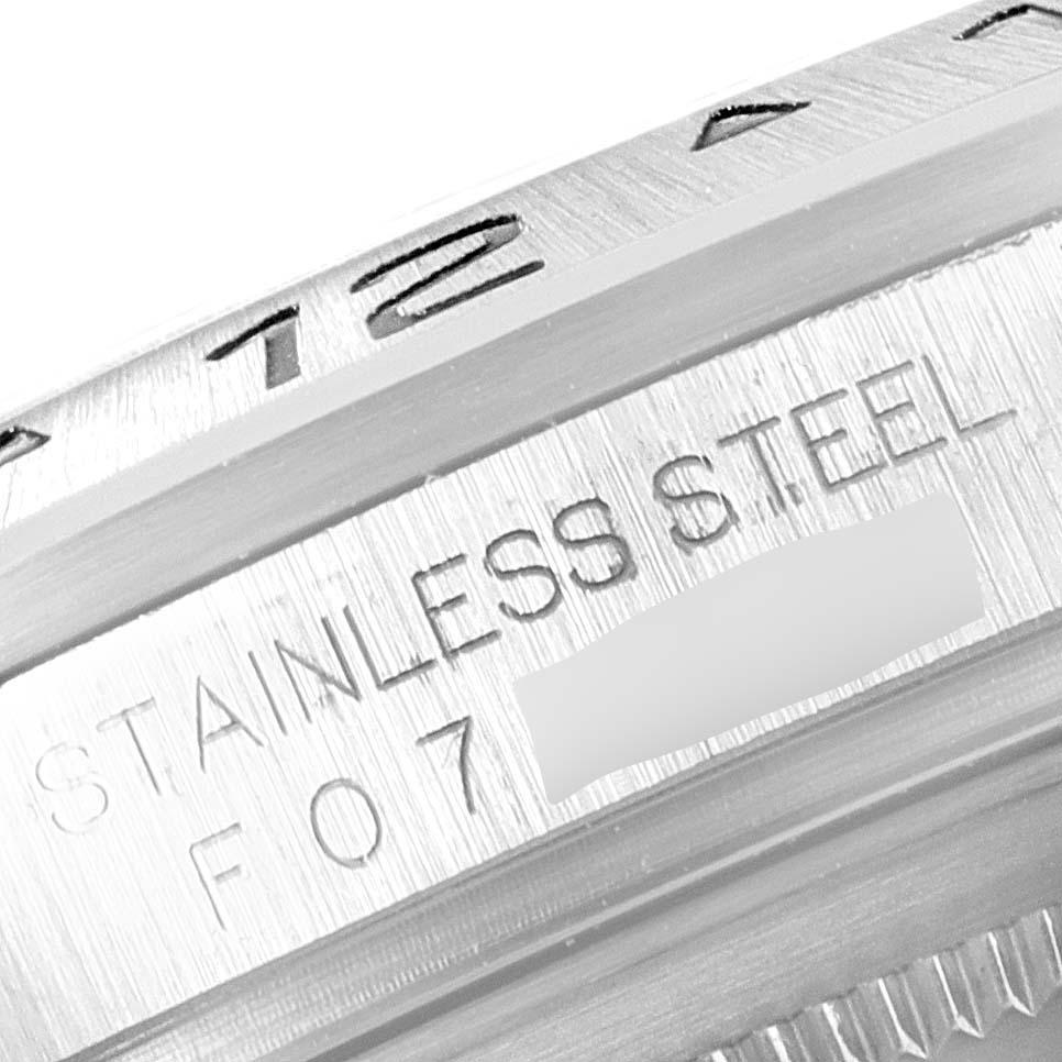 The image shows a close-up of the bezel and inner ring of a Rolex Explorer 16570 Men's Stainless Steel White Dial 16570 Men's Stainless Steel White Dial, highlighting the text "STAINLESS STEEL" and part of a serial number.