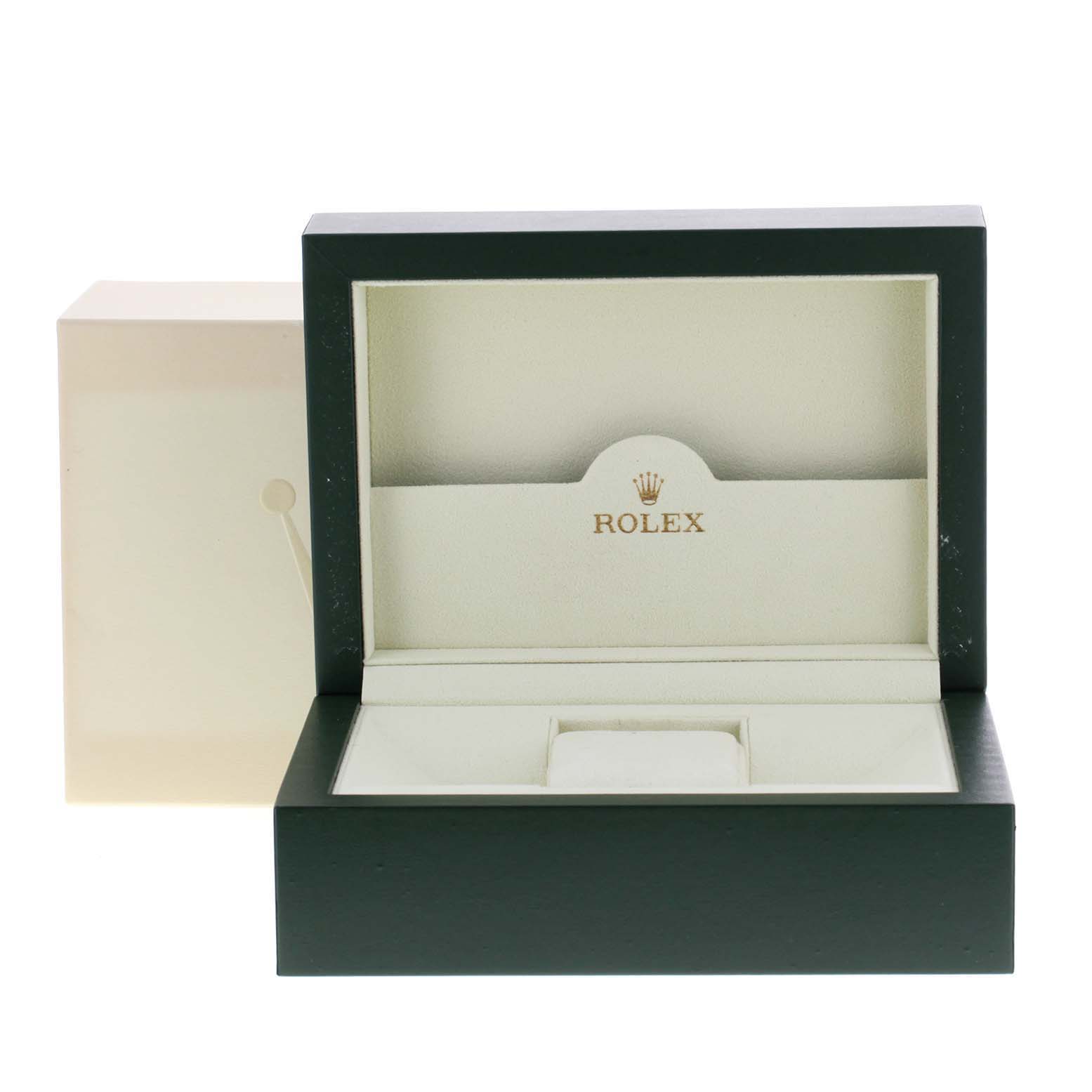 The image shows an open green and beige Rolex box, which likely houses the Submariner model watch.