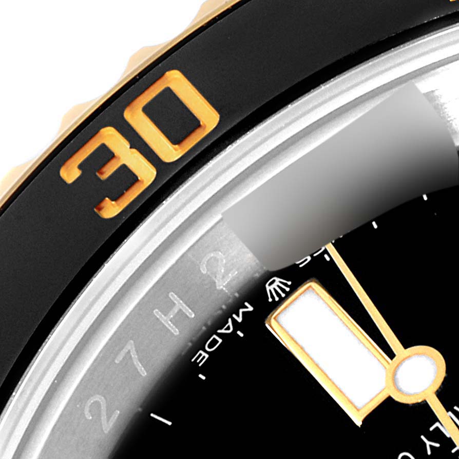 The image shows a close-up of the Rolex Submariner 126613 Men's Steel and Gold (two tone) Black Dial 126613 Men's Steel and Gold (two tone) Black Dial's bezel, dial, and part of the minute hand at an angle.